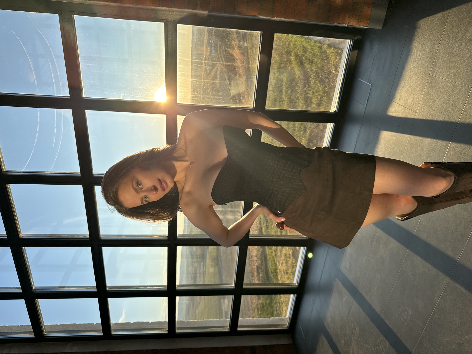 Woman poses by window overlooking sunny landscape in Shamoni