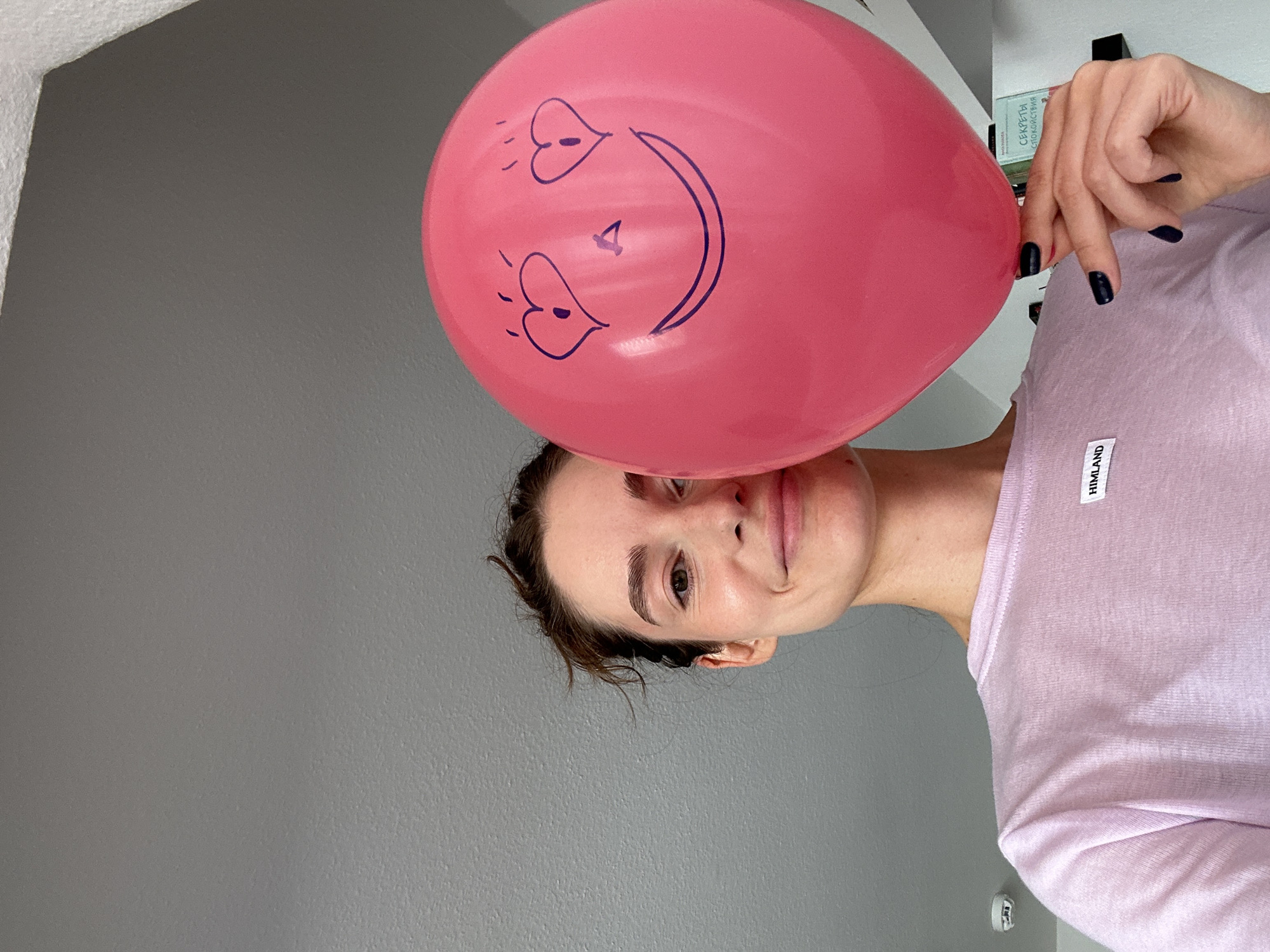 Woman poses with pink balloon against wall in Kiel