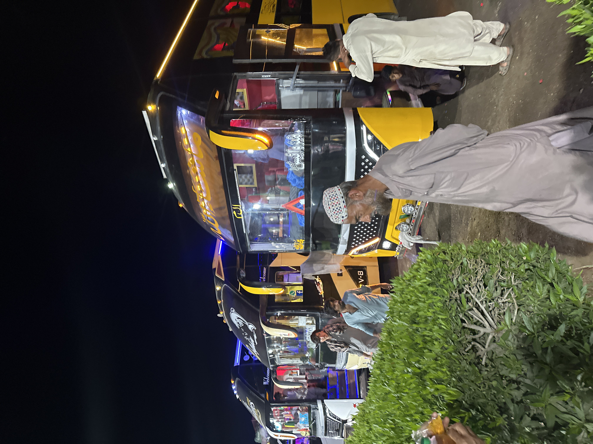 Decorated buses and snack stalls observed at nighttime terminal