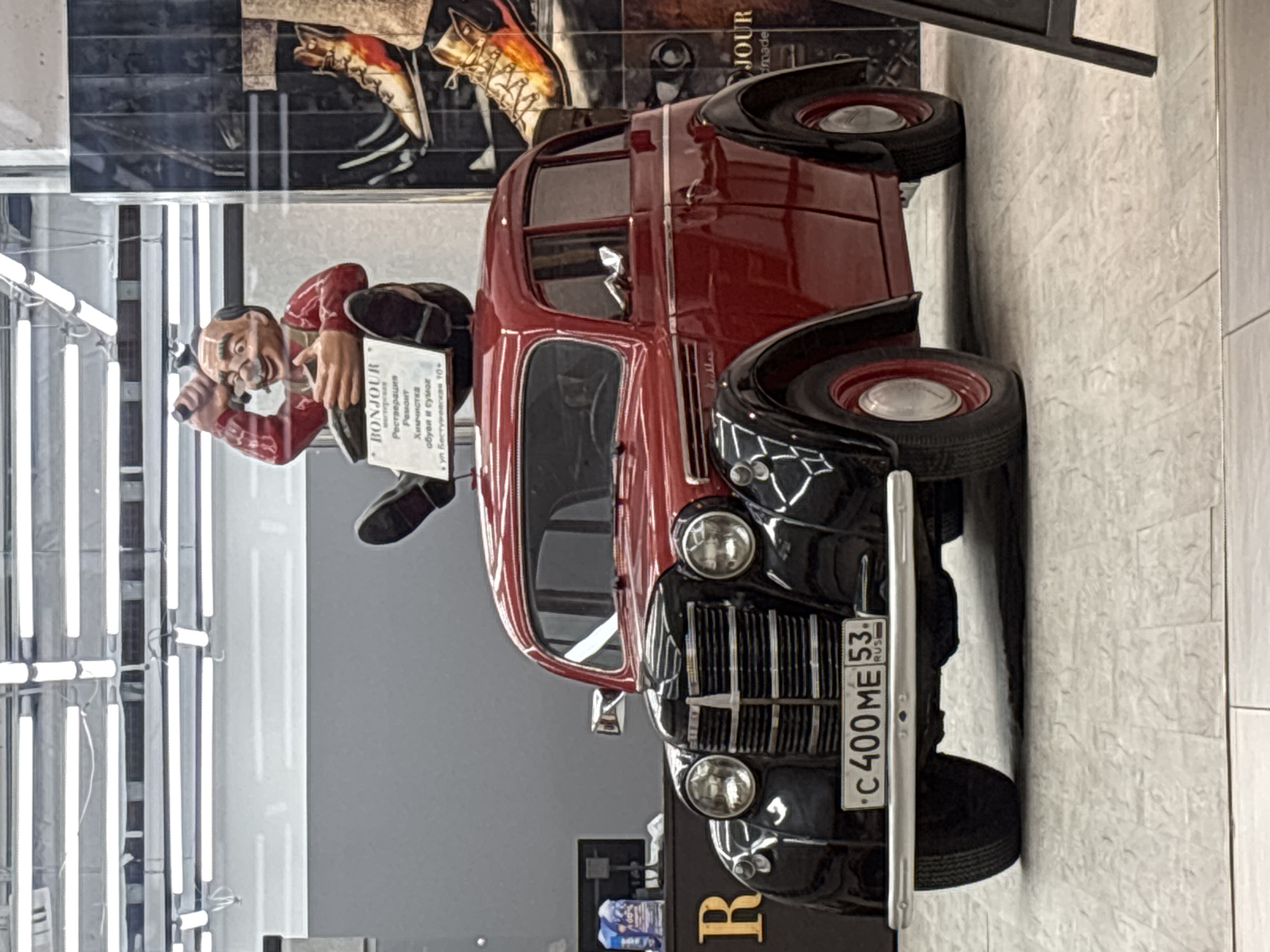 Vintage car art display features whimsical shoemaker figurine