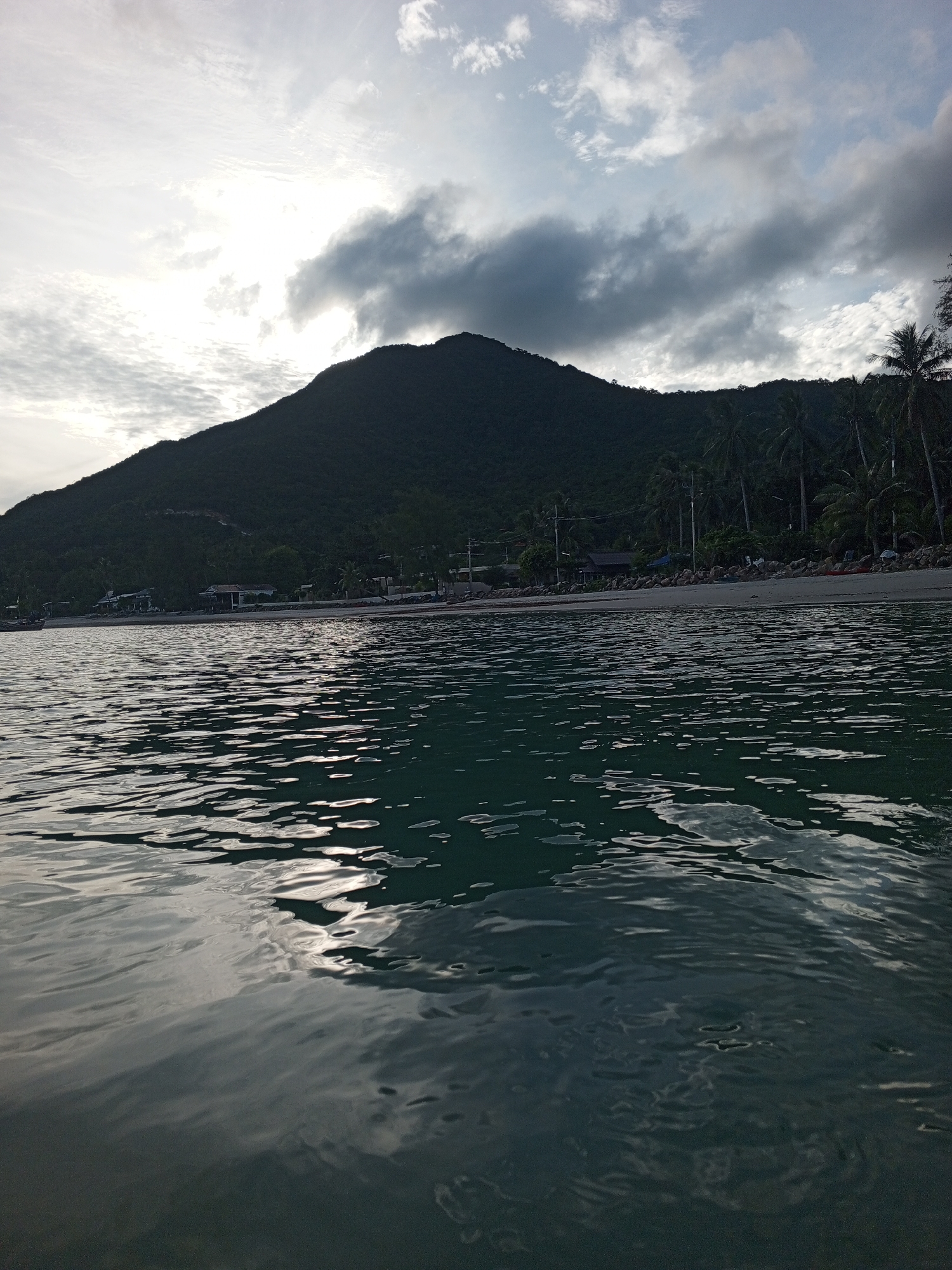 Overcast beach with dramatic mountain backdrop and choppy seas