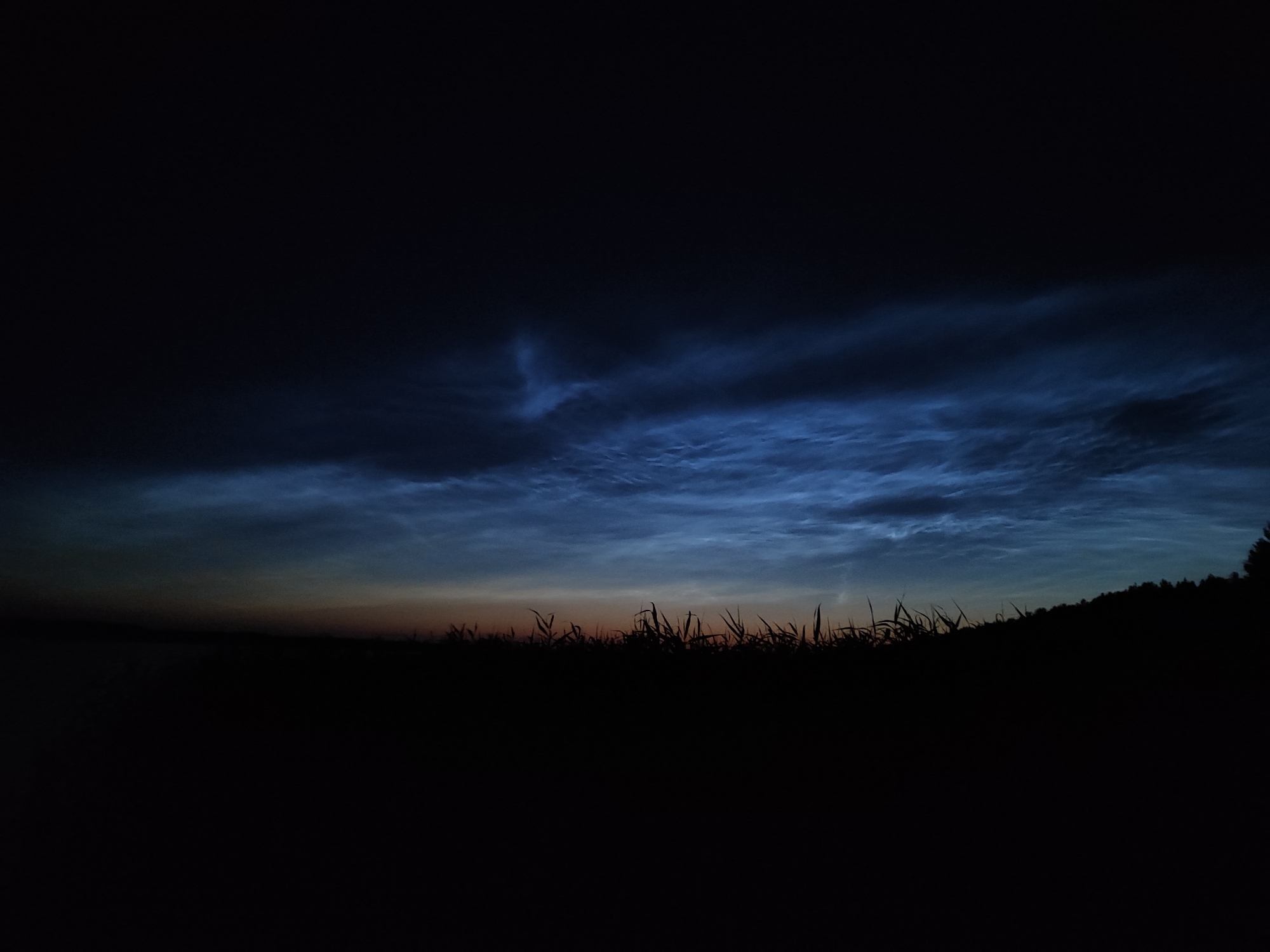Noctilucent clouds and quiet waterfront reflections at dusk