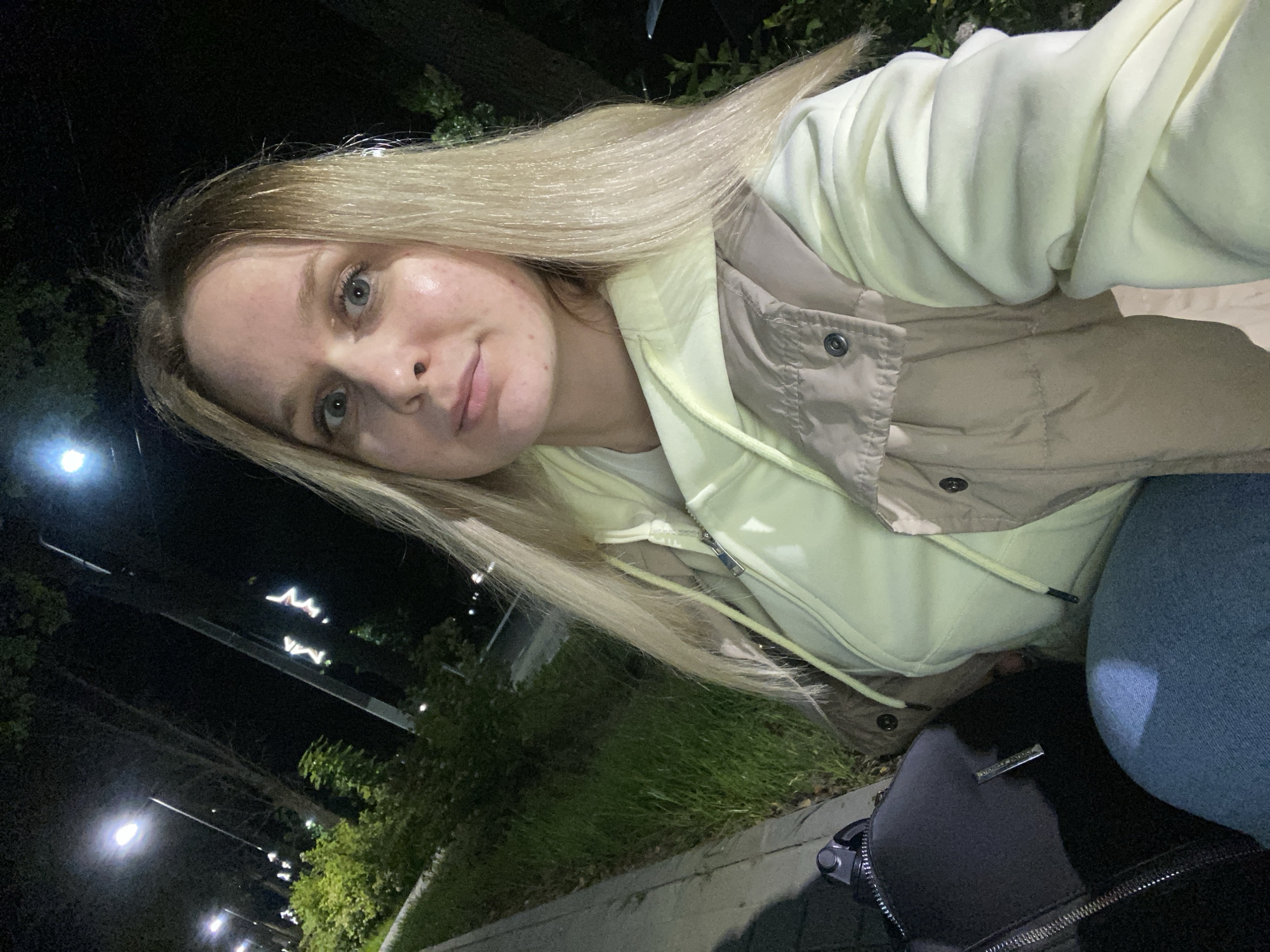 Woman takes nighttime selfies on illuminated walkway in Chaikovsky