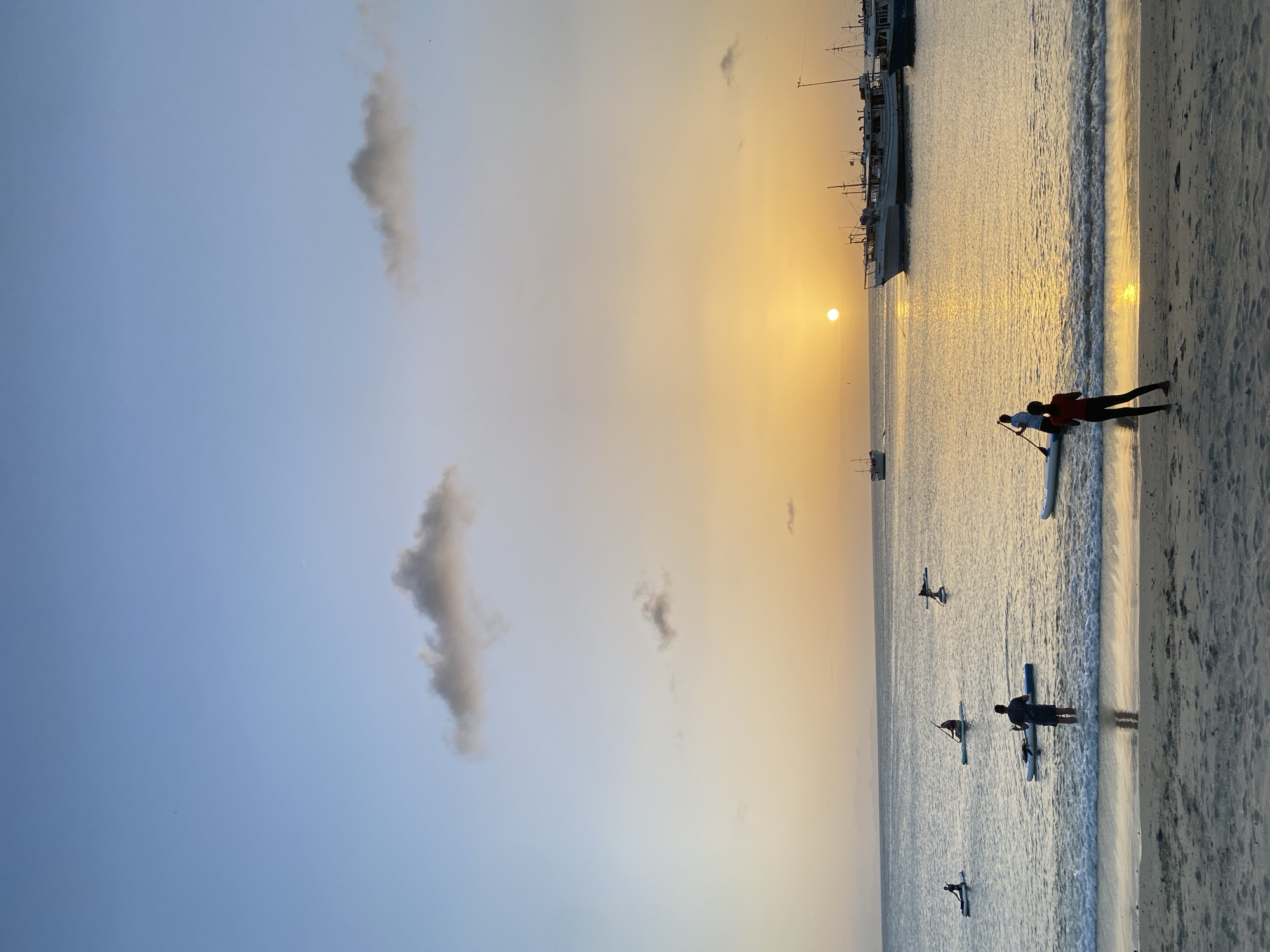 Paddleboarders and beachgoers at sunset in Juan Griego