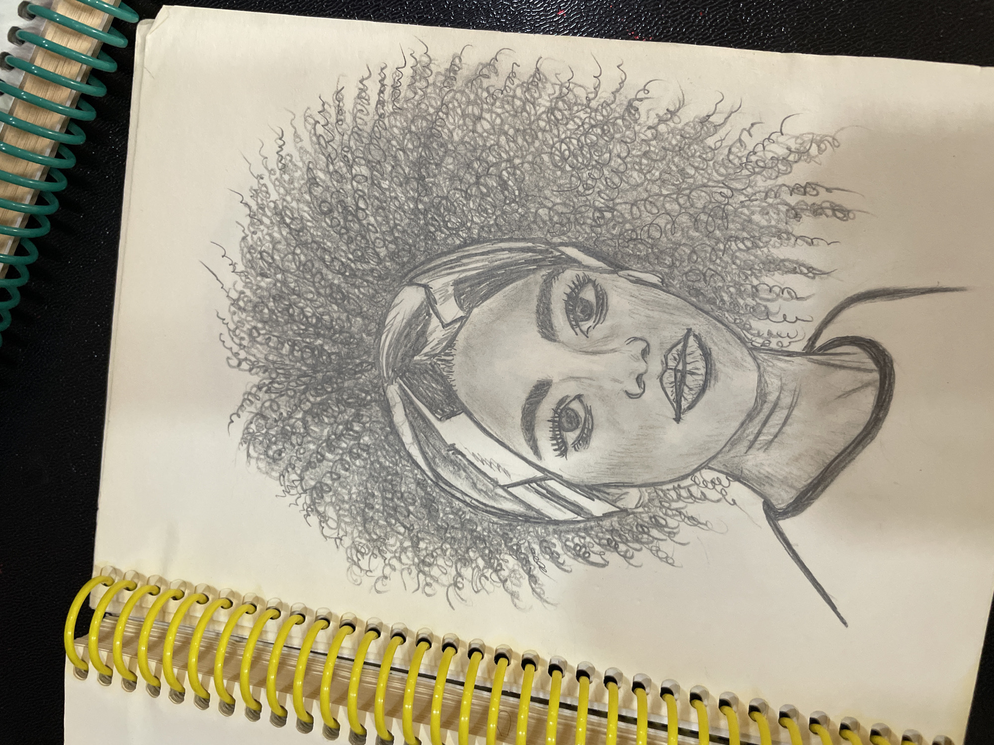 Pencil portrait sketches filling a spiral notebook in Bishkek