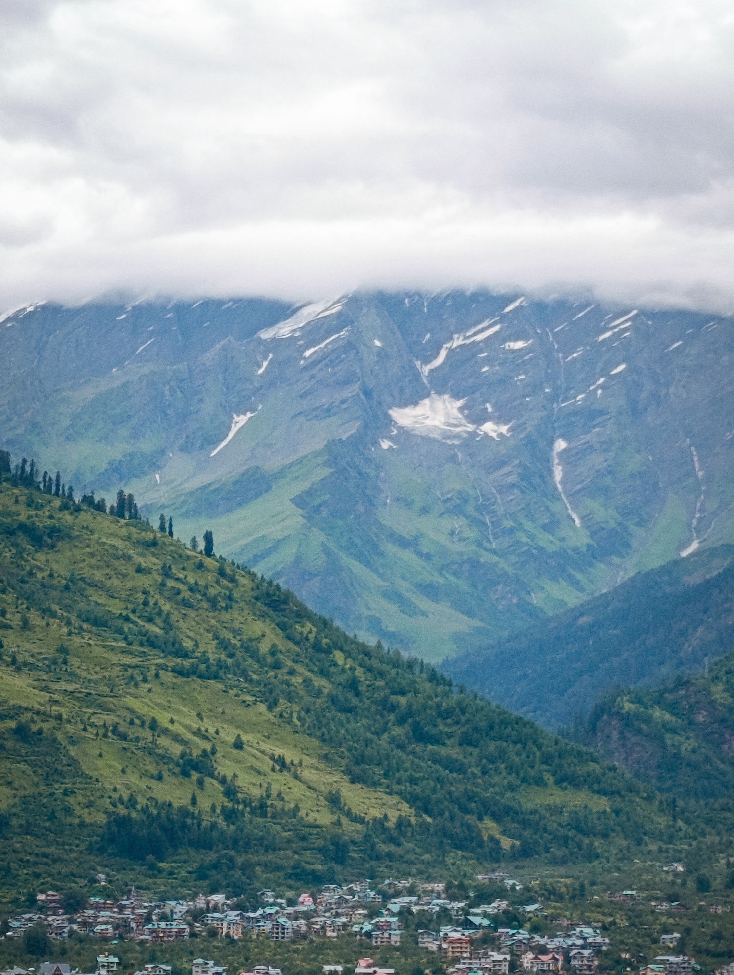 Misty Himalayan peaks and rooftops in Vashisht