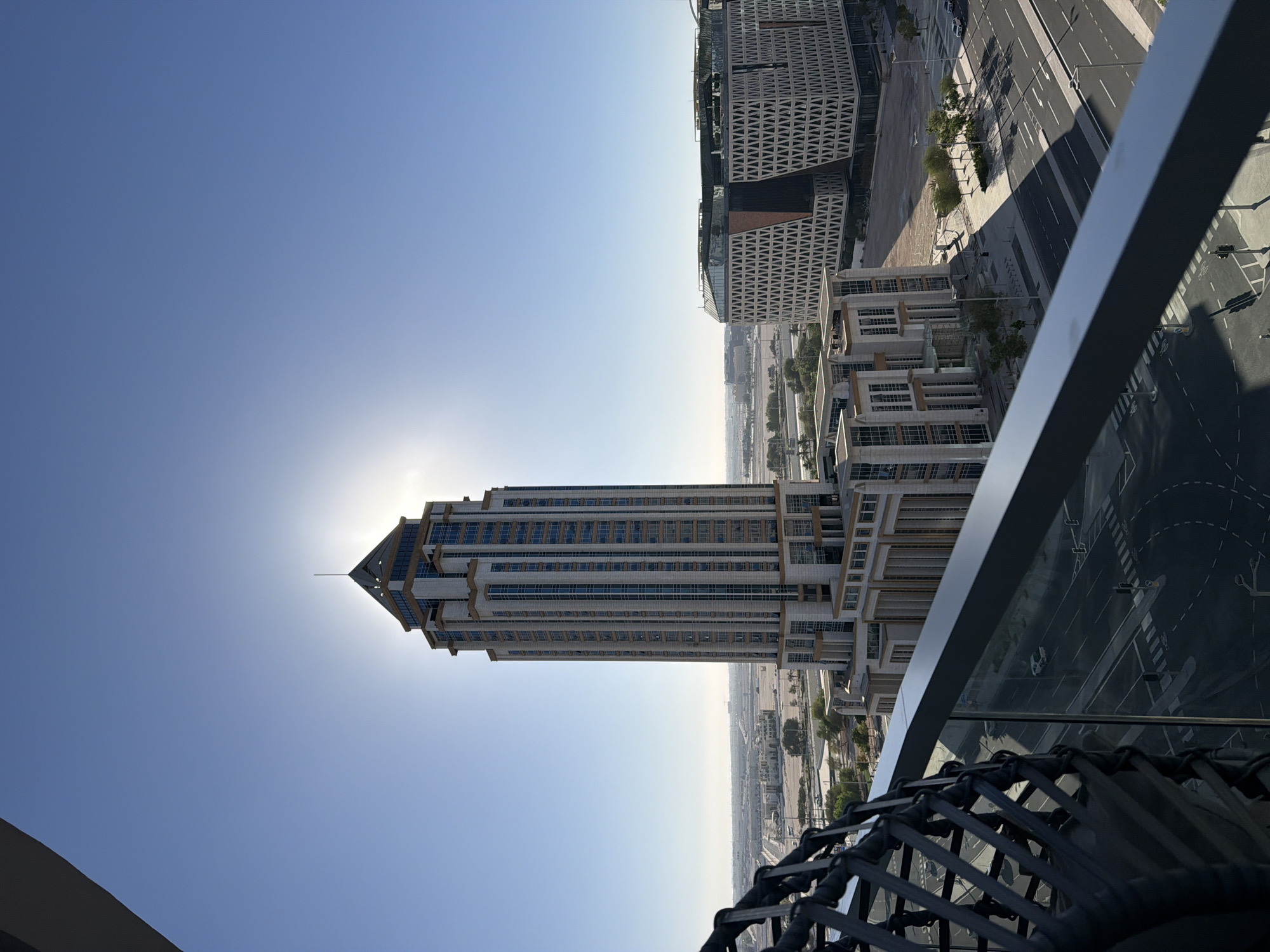 Skyscraper with pointed top dominates sunny city intersection