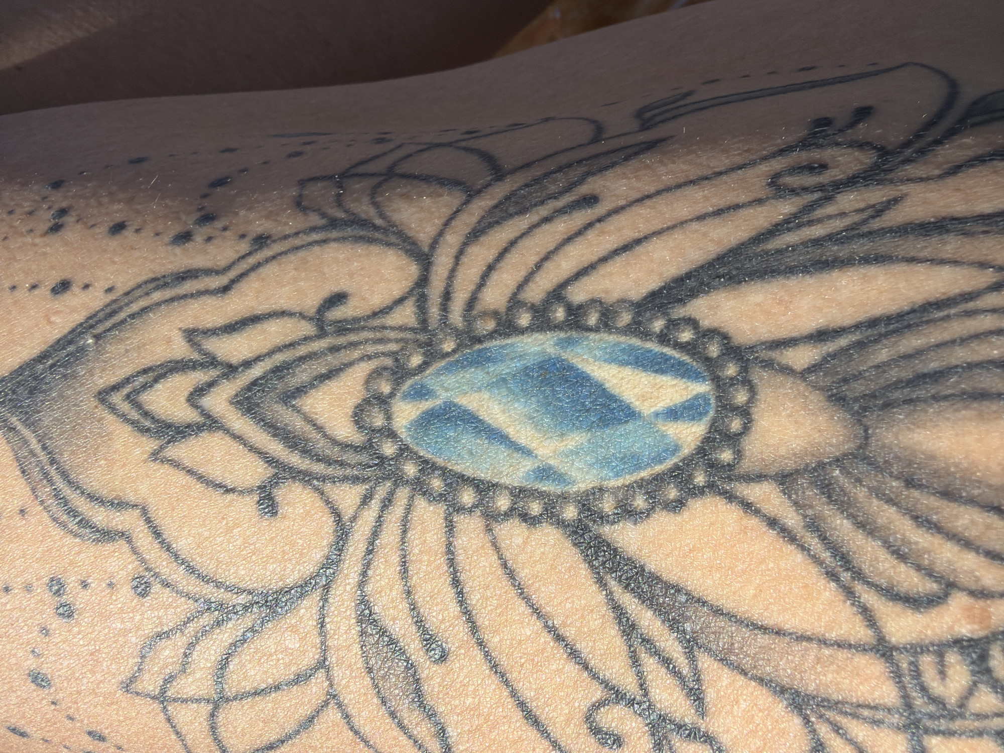 Floral tattoo with blue geometric pattern documented in Al Hadaba
