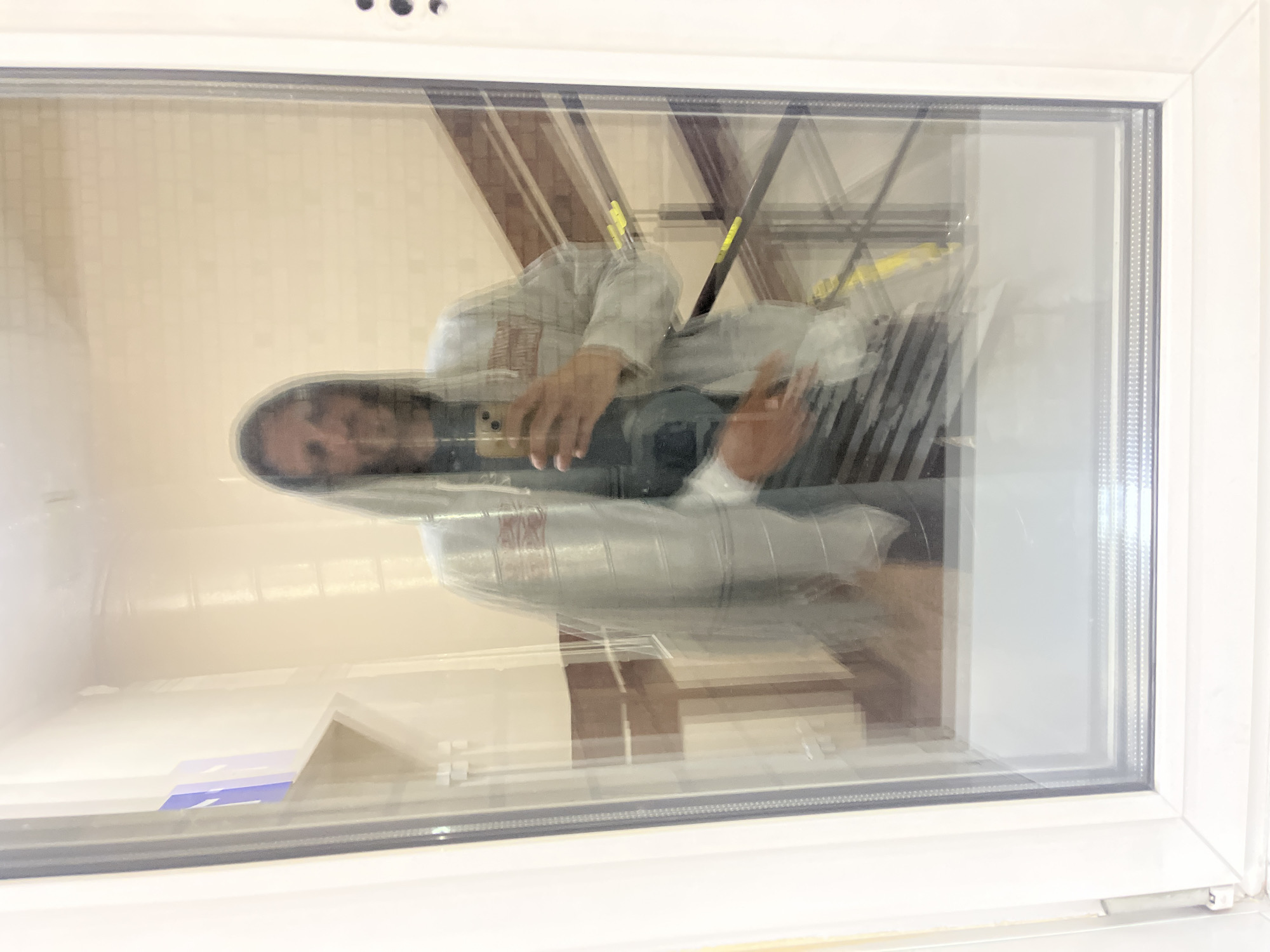 Person photographing through glass panel, composite floor surface documented