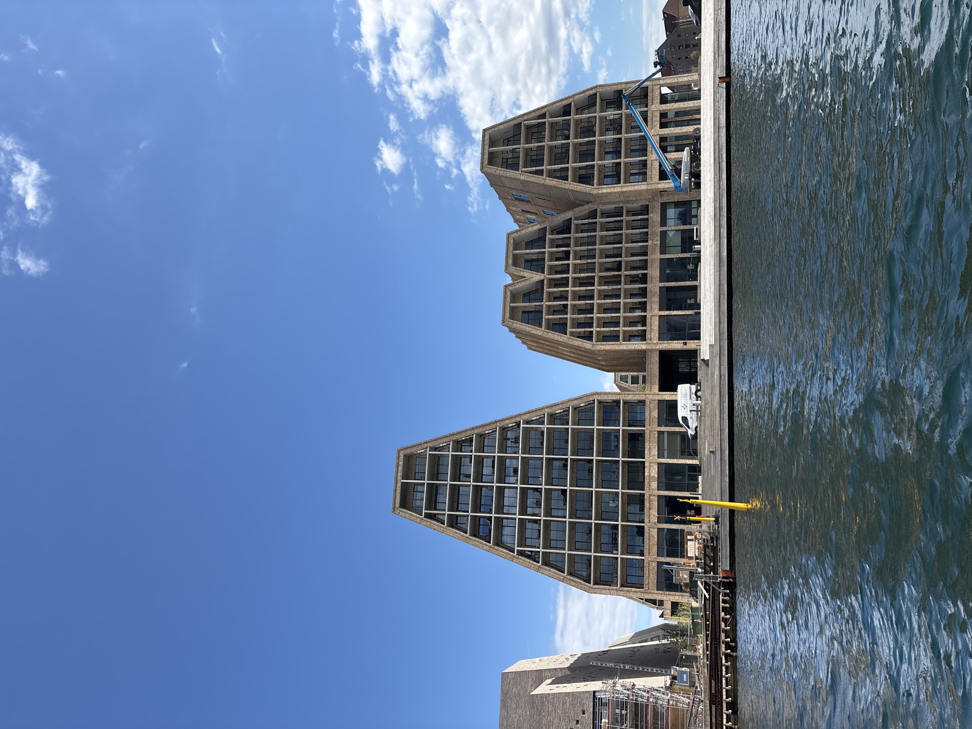 Water bus travels Copenhagen harbor past modern waterfront buildings