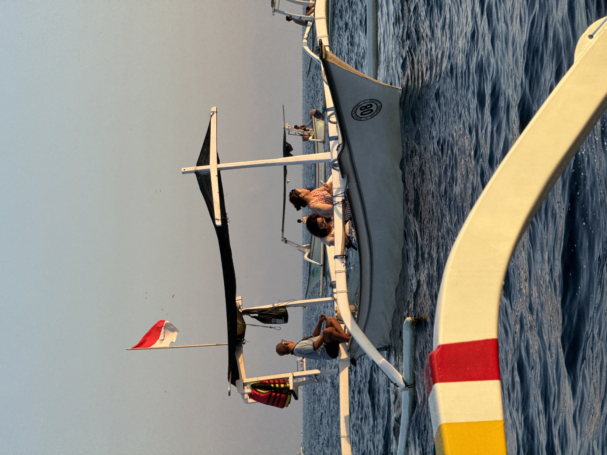 Traditional outrigger boats cross Bali's waters at sunset
