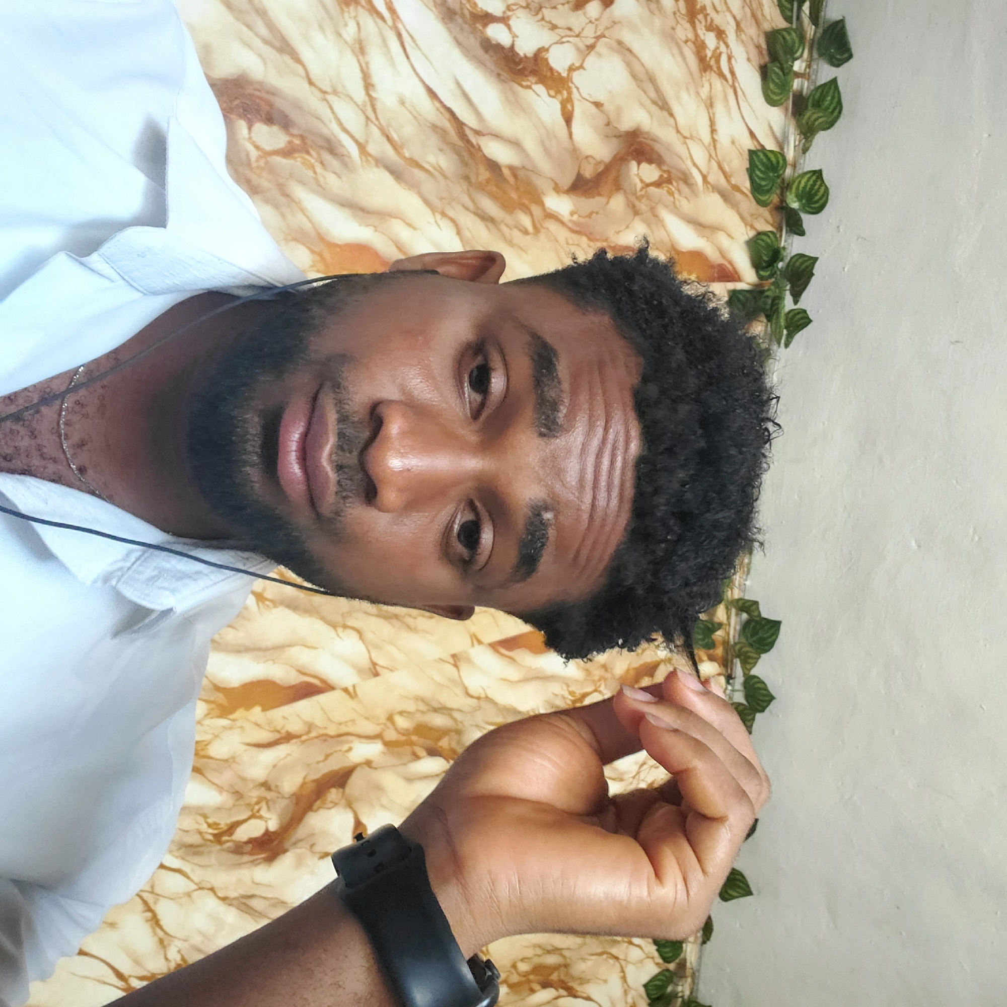 Man in white shirt poses on green couch in Nkpor