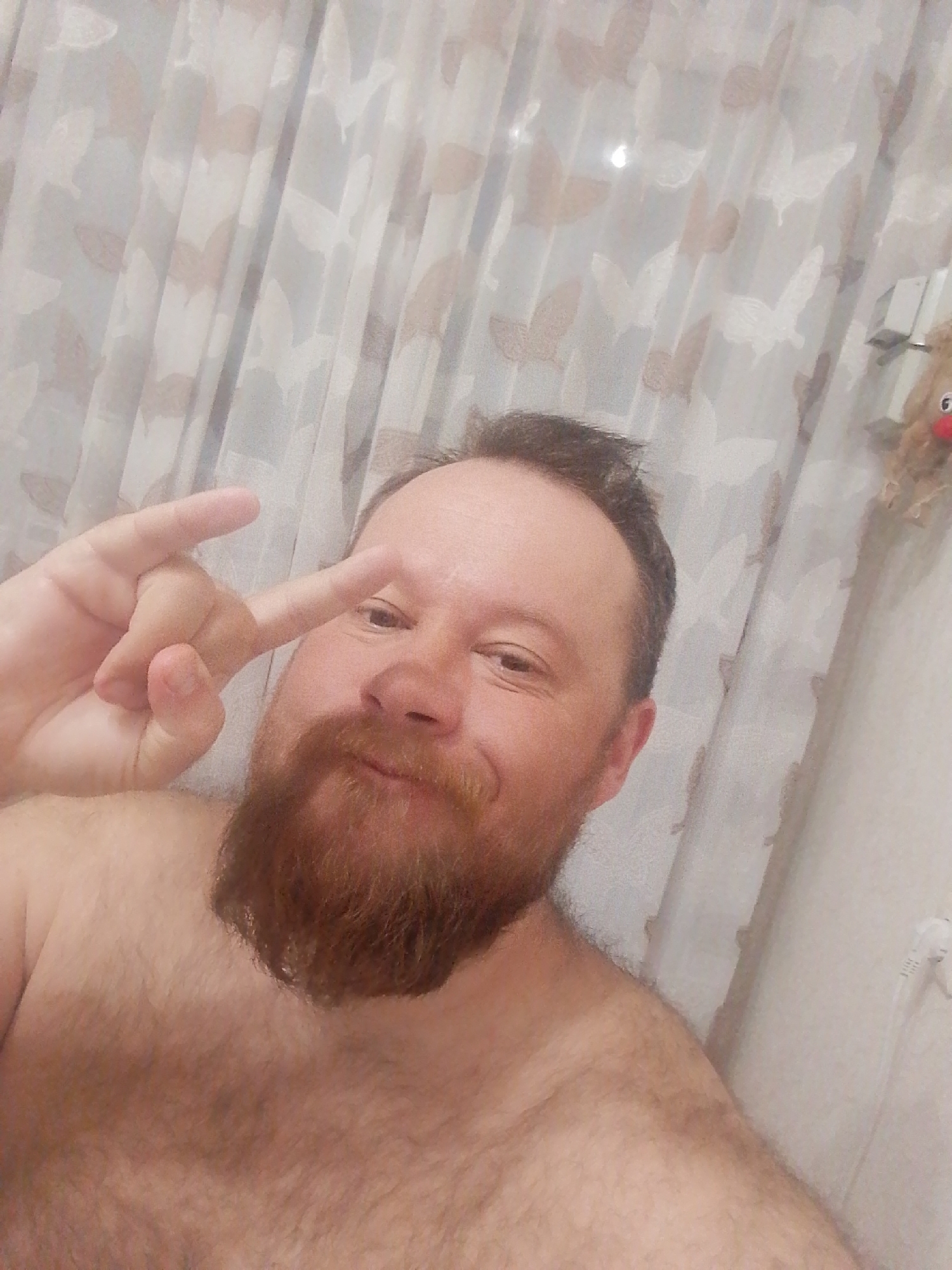 Man poses shirtless indoors in Russian home setting