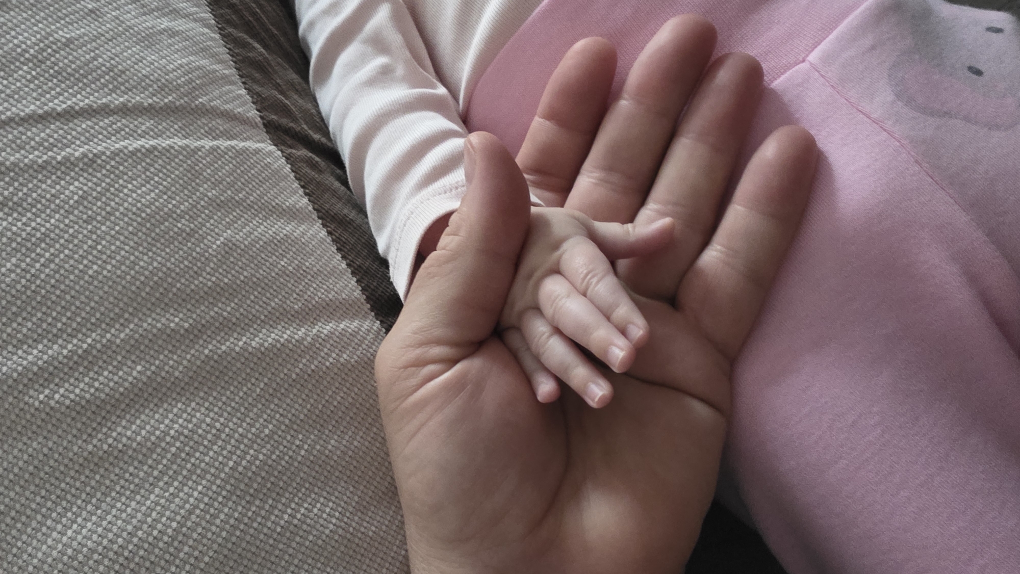 Adult tenderly holds baby in early morning moment, Bulgaria