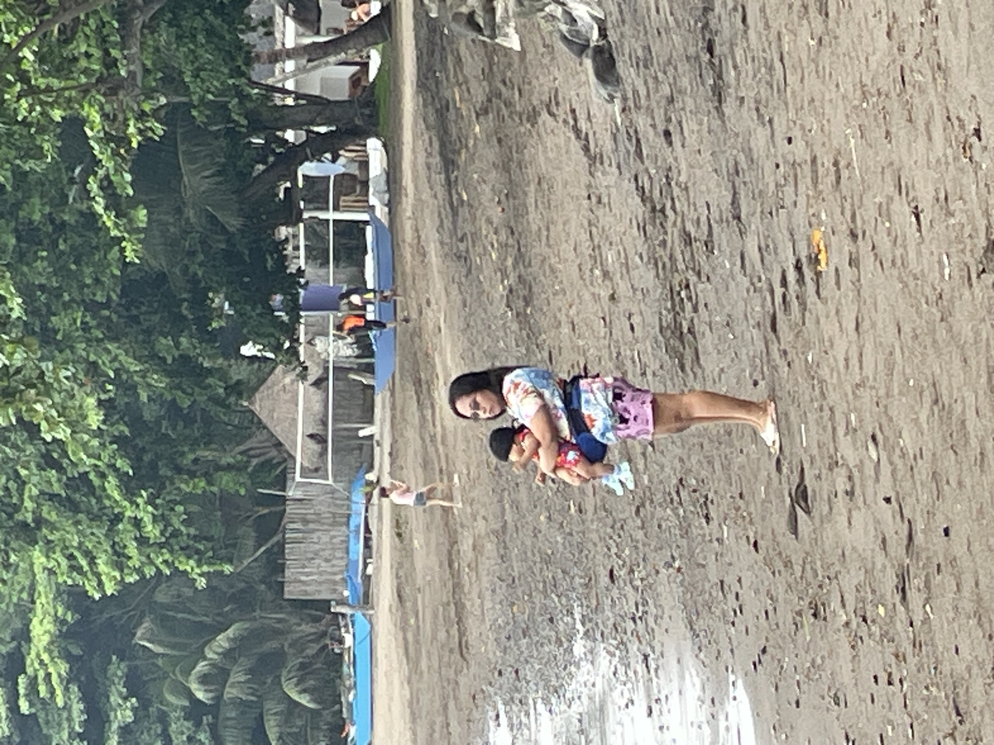 Dauin beach morning: divers, boats, and a baby in tow