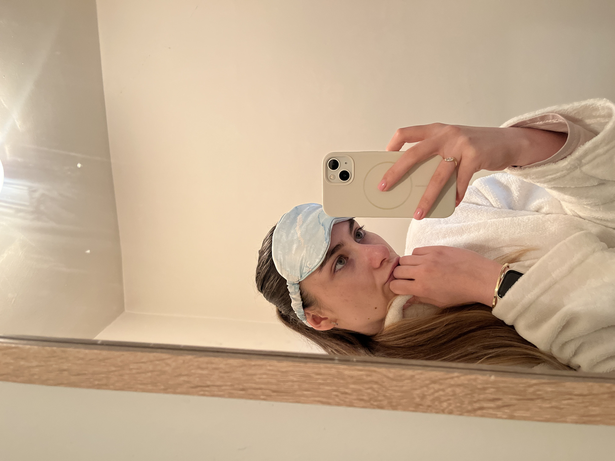 Woman takes bathroom mirror selfies wearing sleep mask and robe