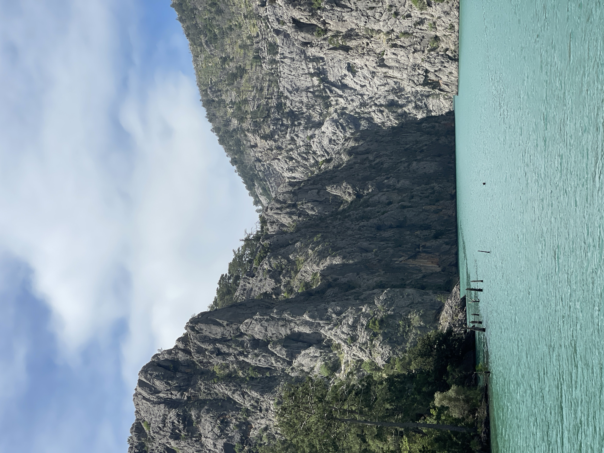 Boat crosses turquoise mountain lake under cloudy skies