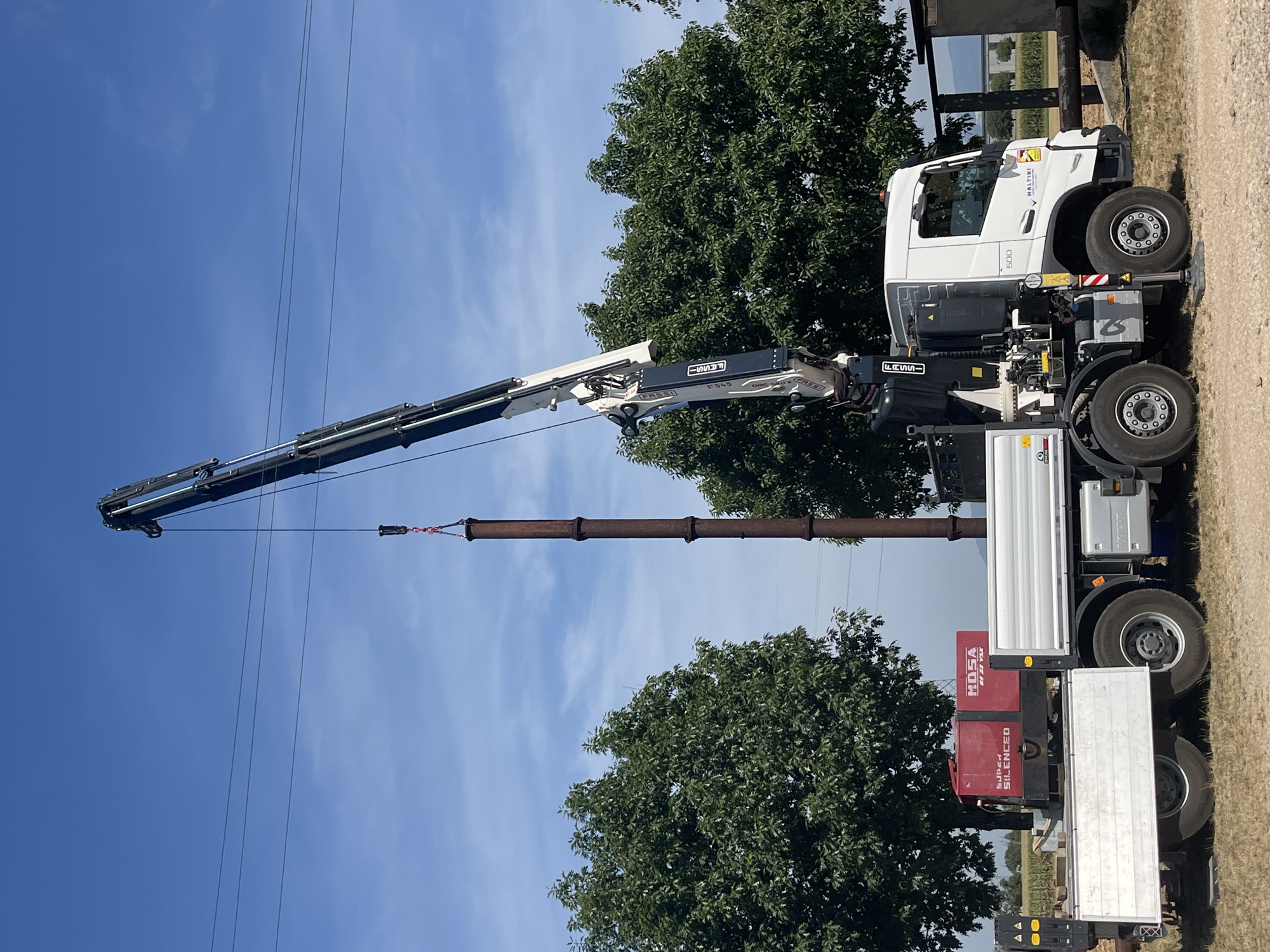 Crane crew moves rusty pipes at a working farm in northern Italy