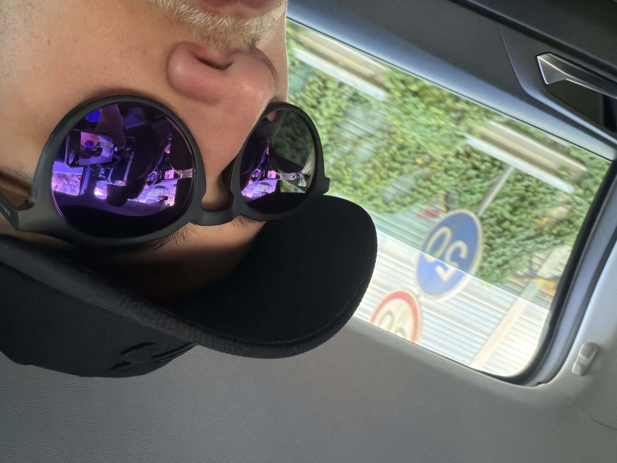 Person in vehicle with arcade lights reflected in sunglasses