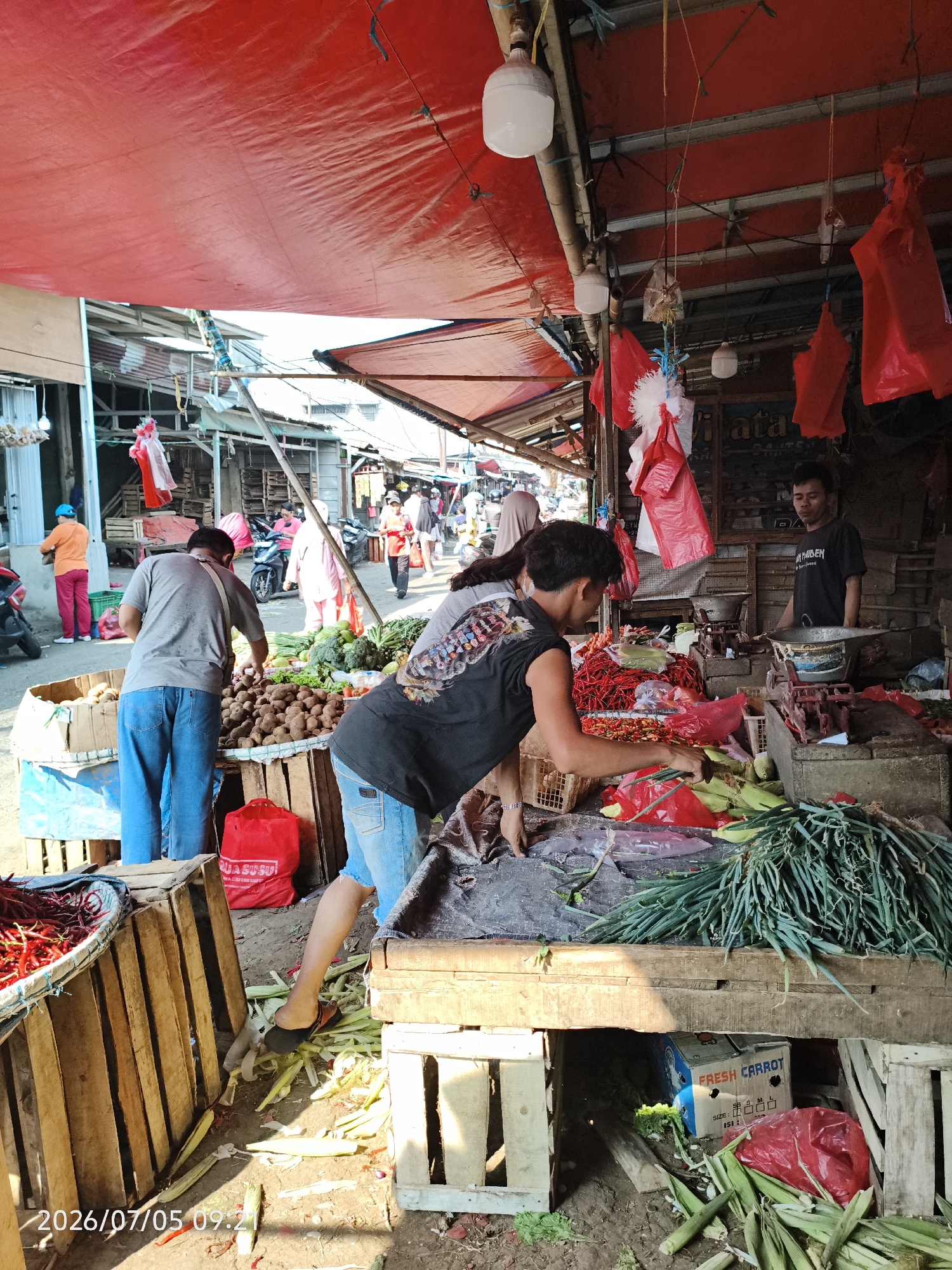 Outdoor produce stall under a red tarp in Depok