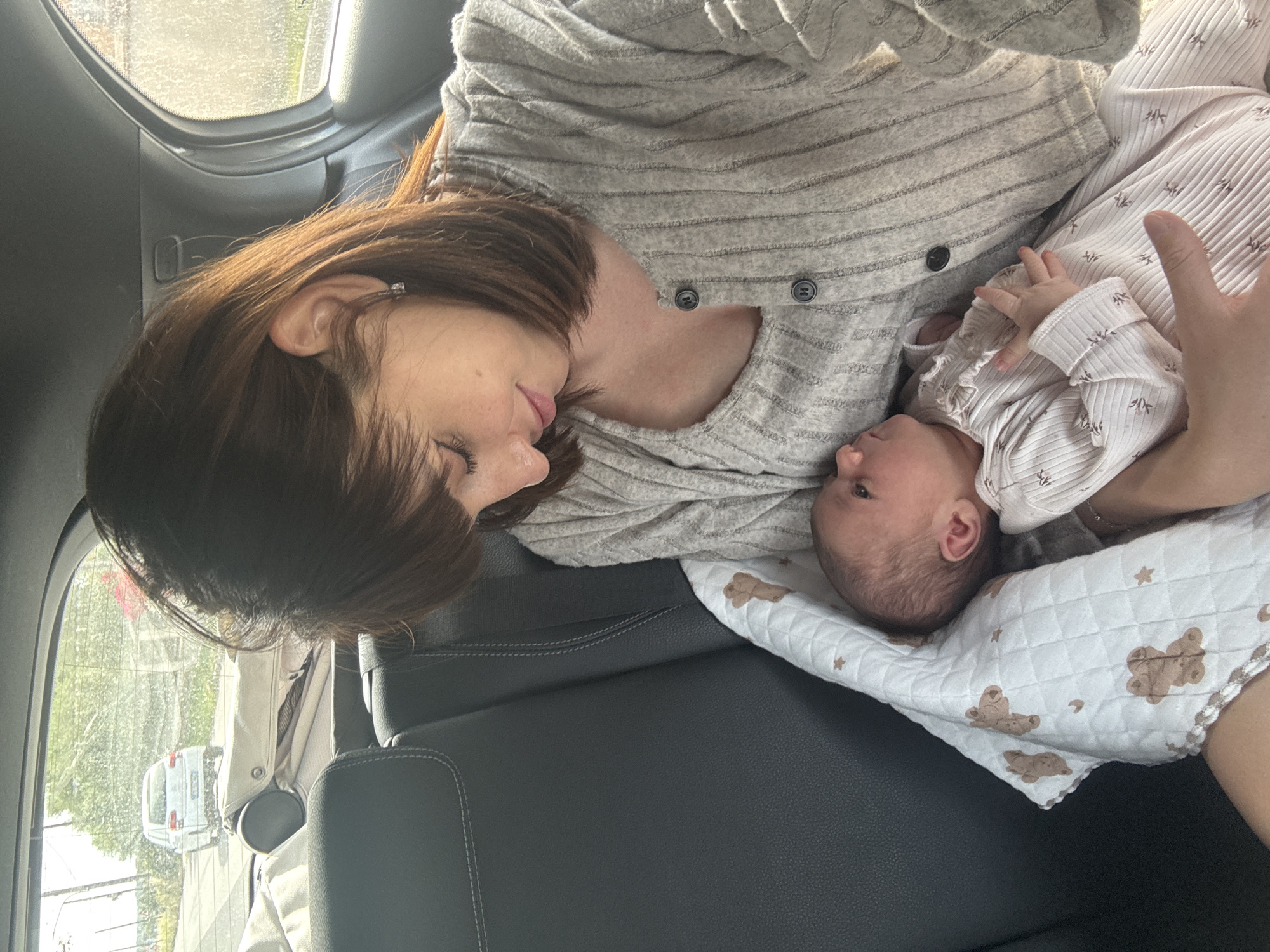 Mother holds newborn baby in car backseat, Nettuno Italy