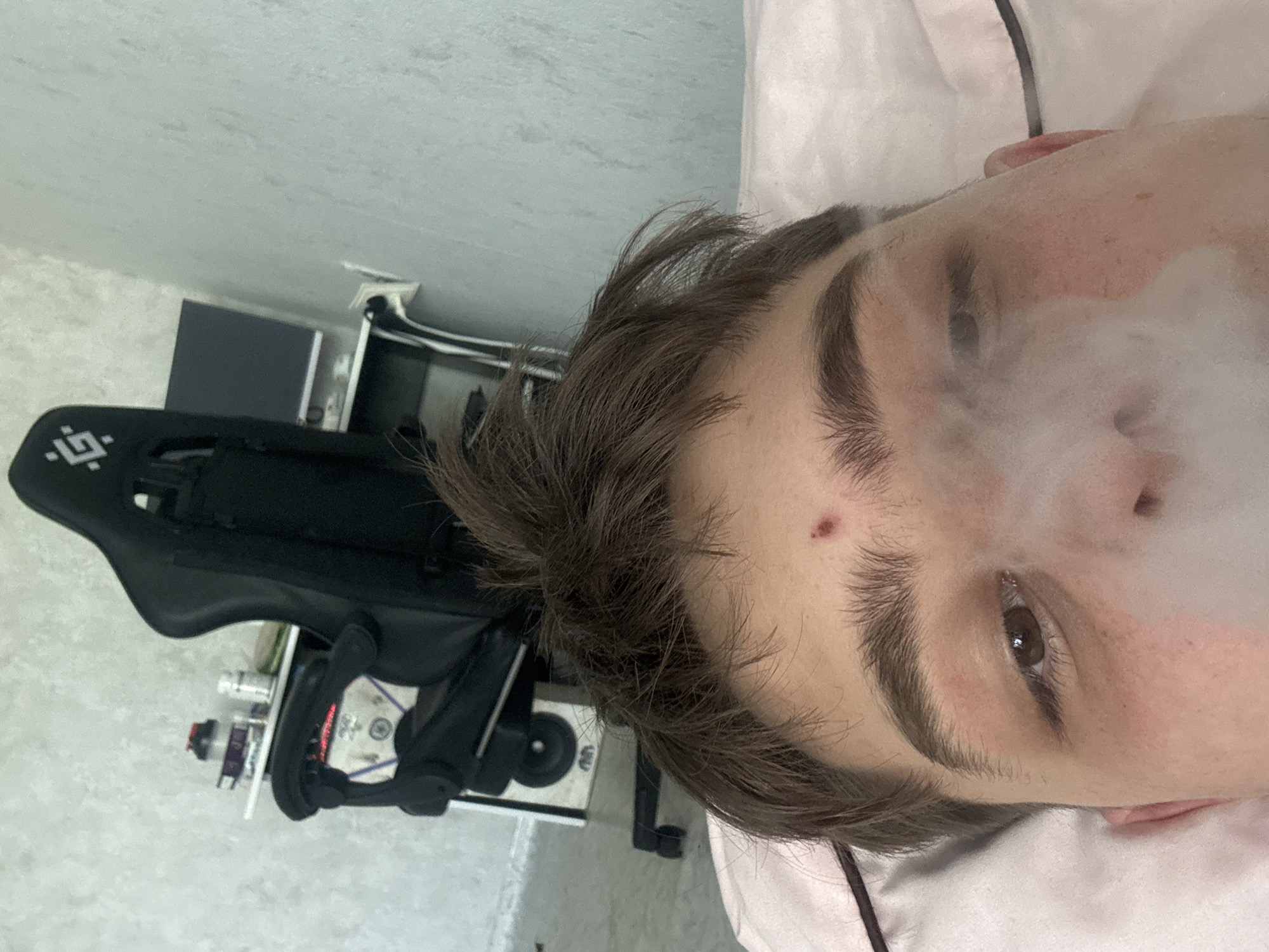 Person with tattoo vaping indoors during early morning hours