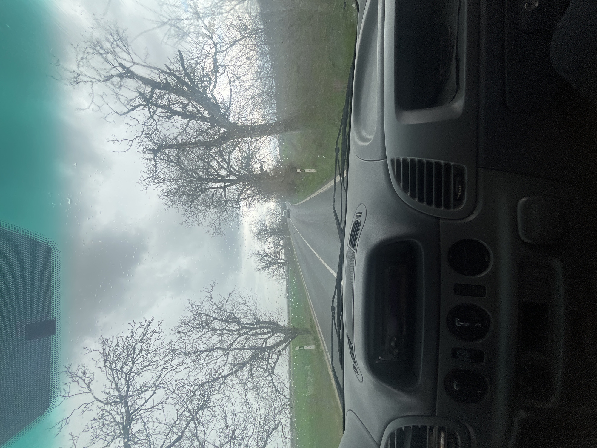 Vehicle travels wet road in overcast Bulgarian countryside