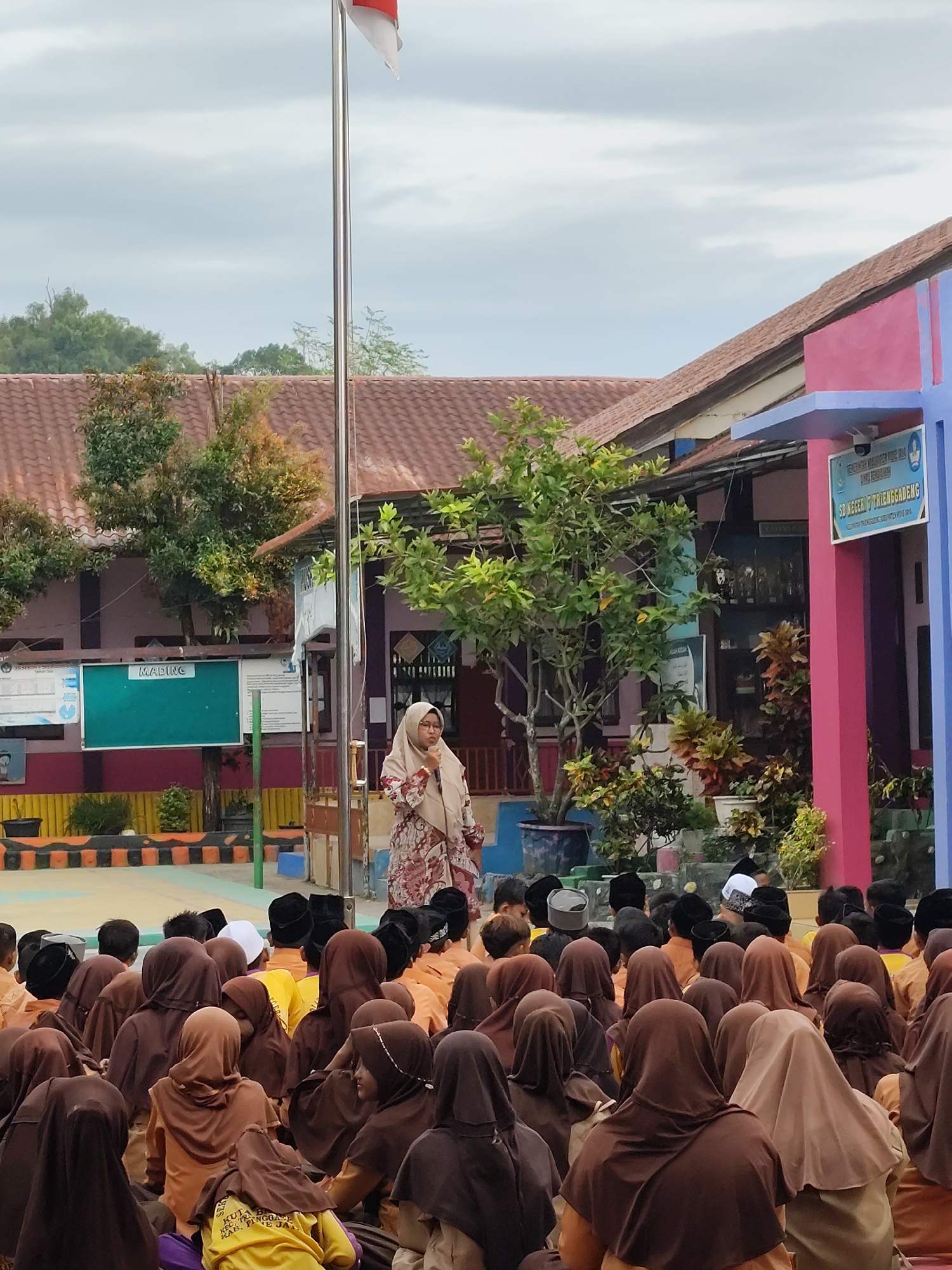 School assembly in session, students gathered outdoors on colorful mats