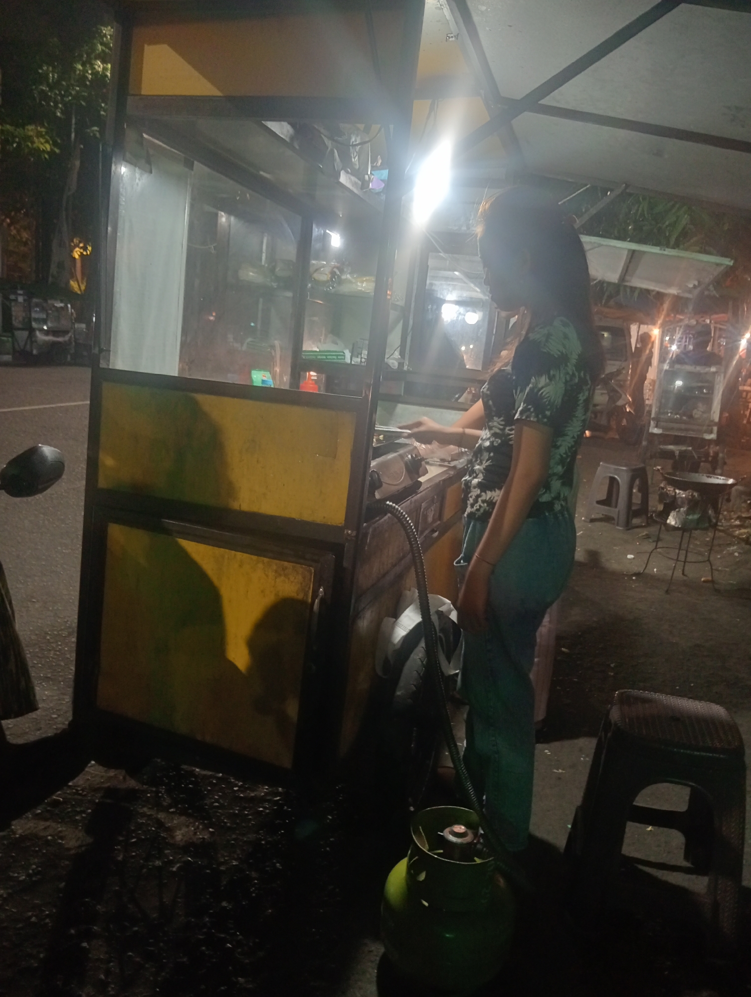 Helmeted rider stops at a Surabaya street food cart at night