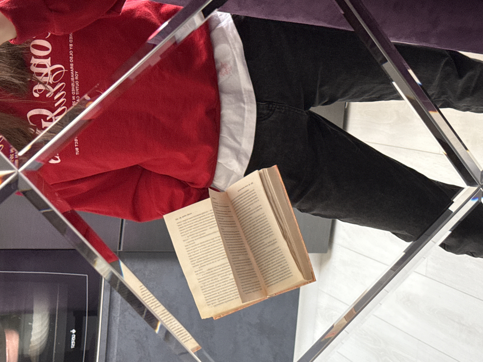 Person reading Cyrillic book captured through mirrors in home