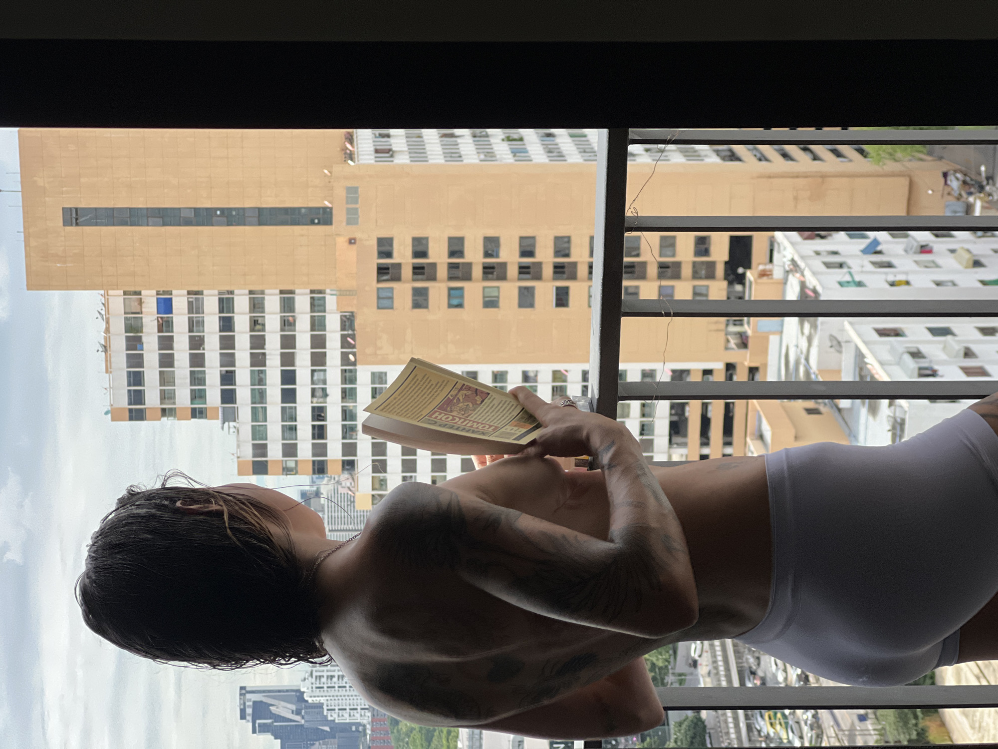 Tattooed figure overlooks Bangkok's dense cityscape from a balcony
