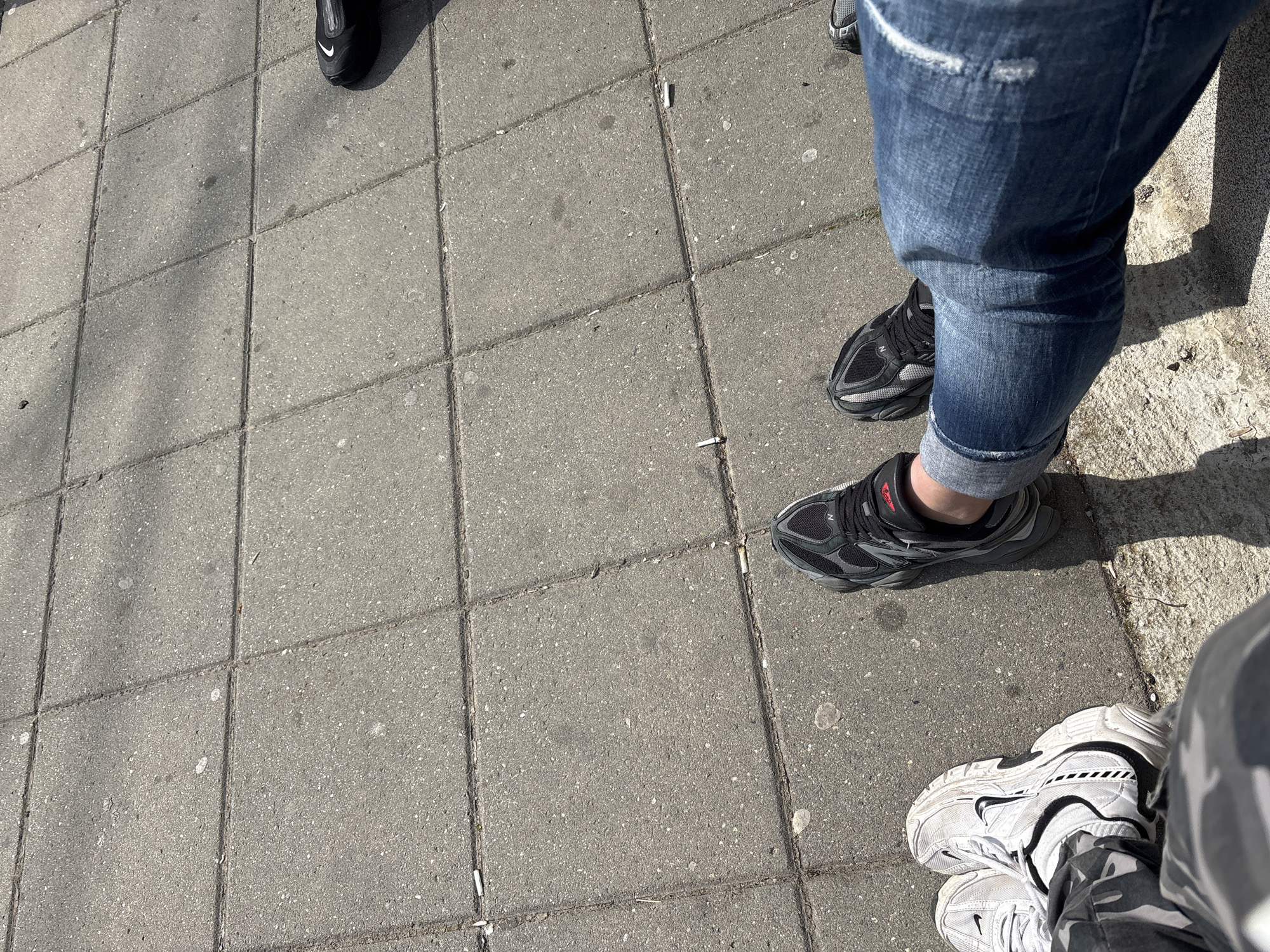 Three people's feet photographed on concrete pavement in Bulgaria