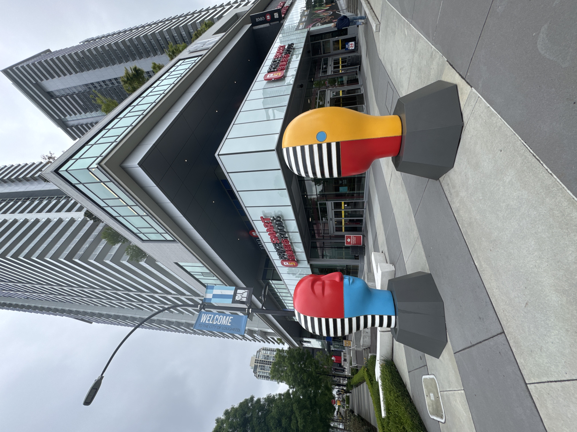 Colorful abstract head sculptures displayed on Burnaby pedestrian pavement