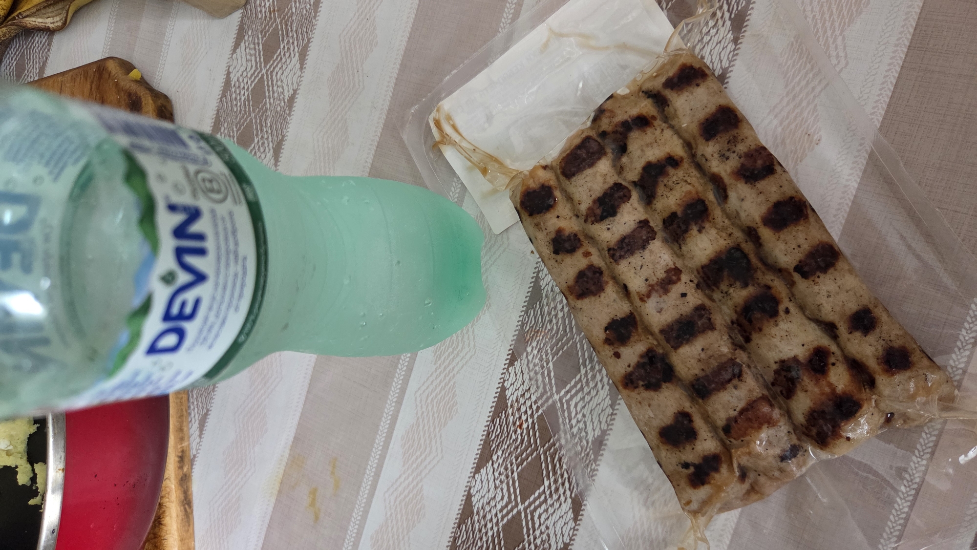Grilled sausages, mineral water, and a poster-covered cabinet