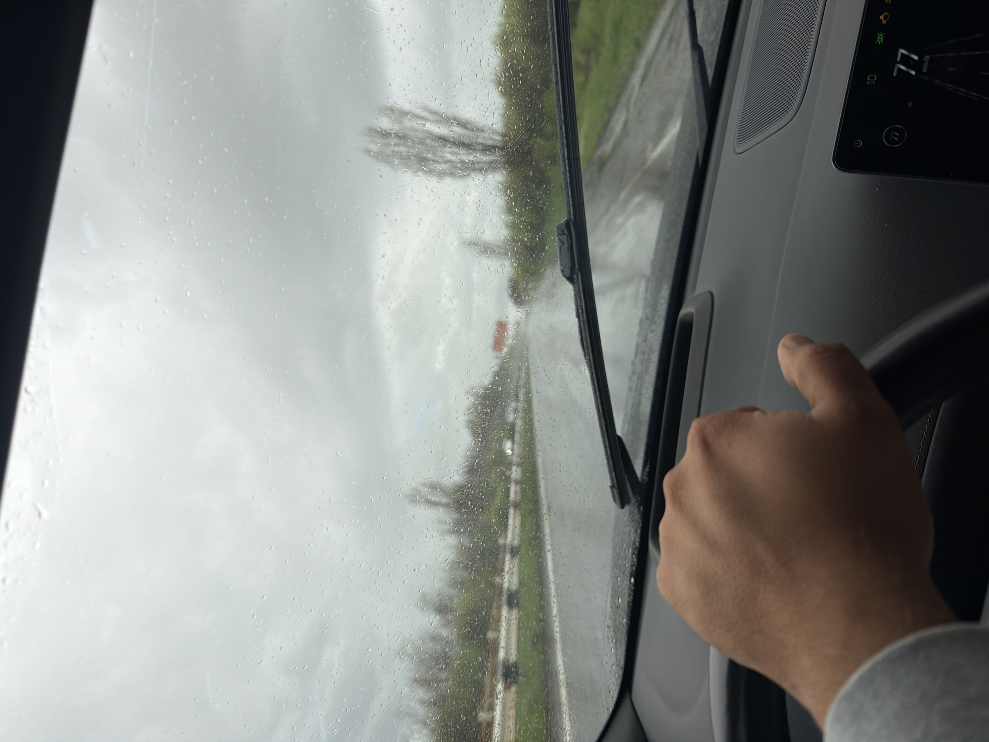 Driver travels past hilltop monastery during morning rain