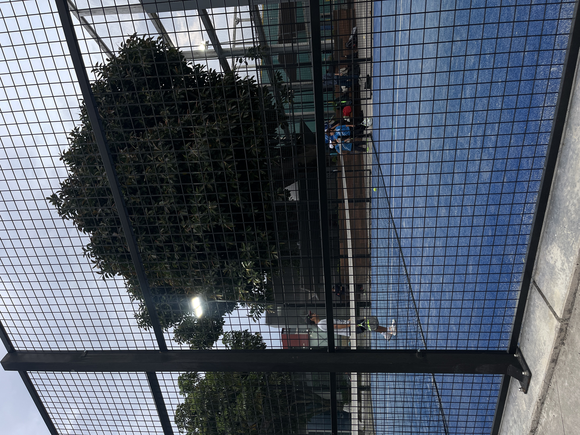 Late night paddle tennis player captured mid-swing on blue court