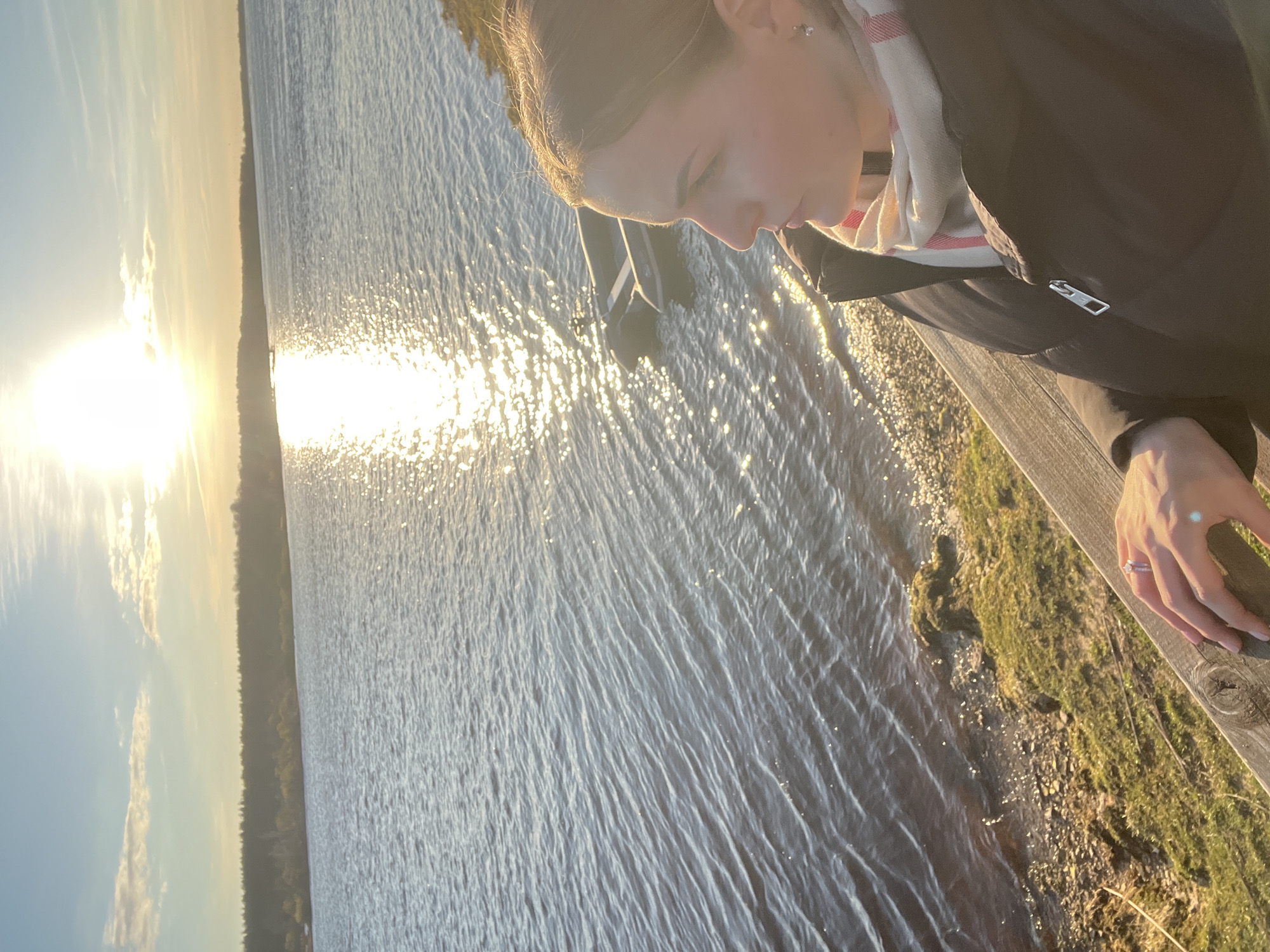 Woman watches sunset by water in Riga, Latvia