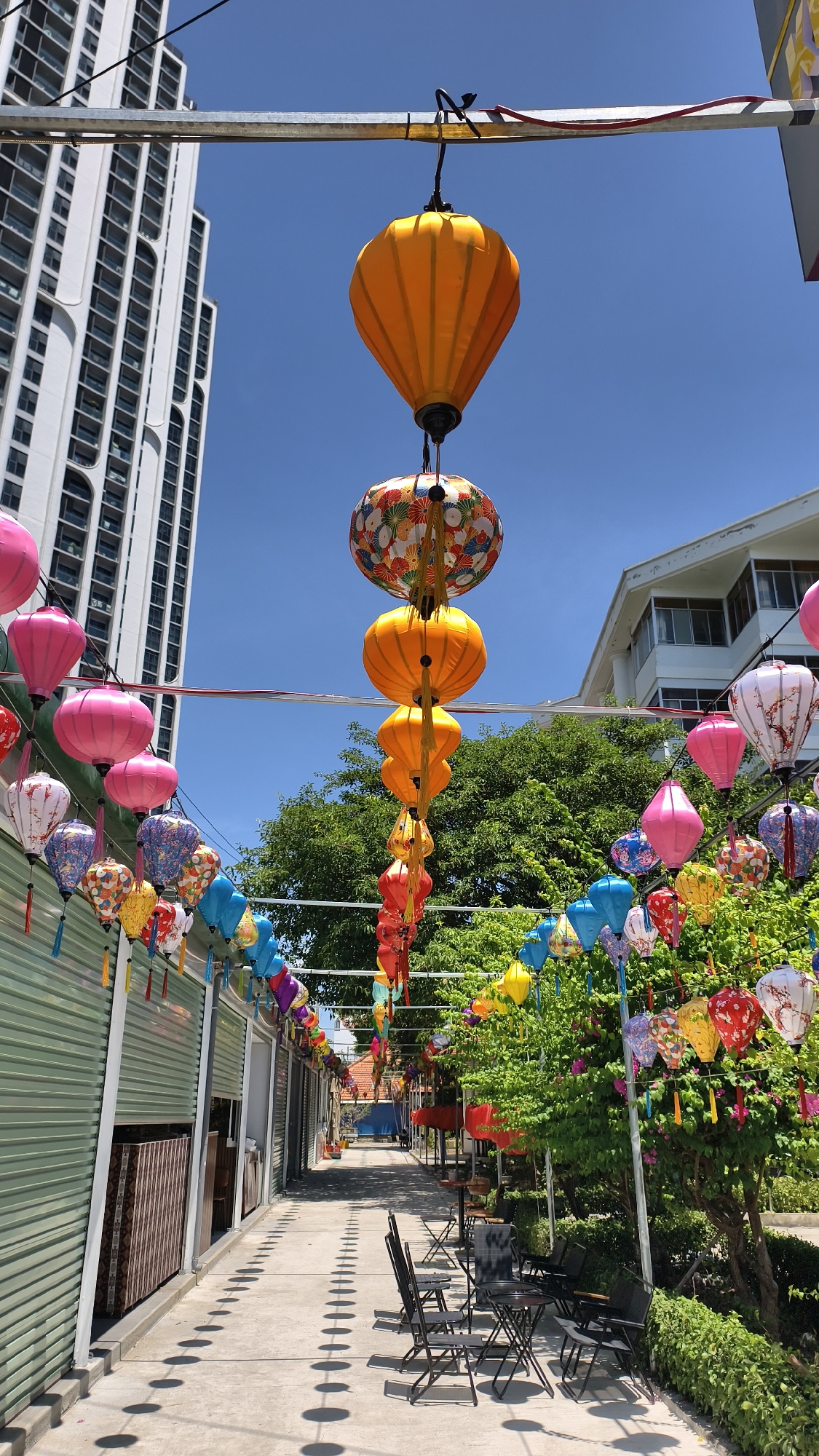 Lantern-strung street and twin-spired church under blue skies