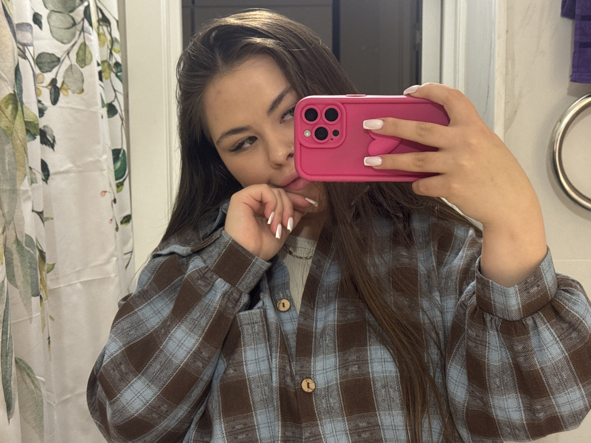 Woman takes bathroom selfie with pink heart-detailed smartphone