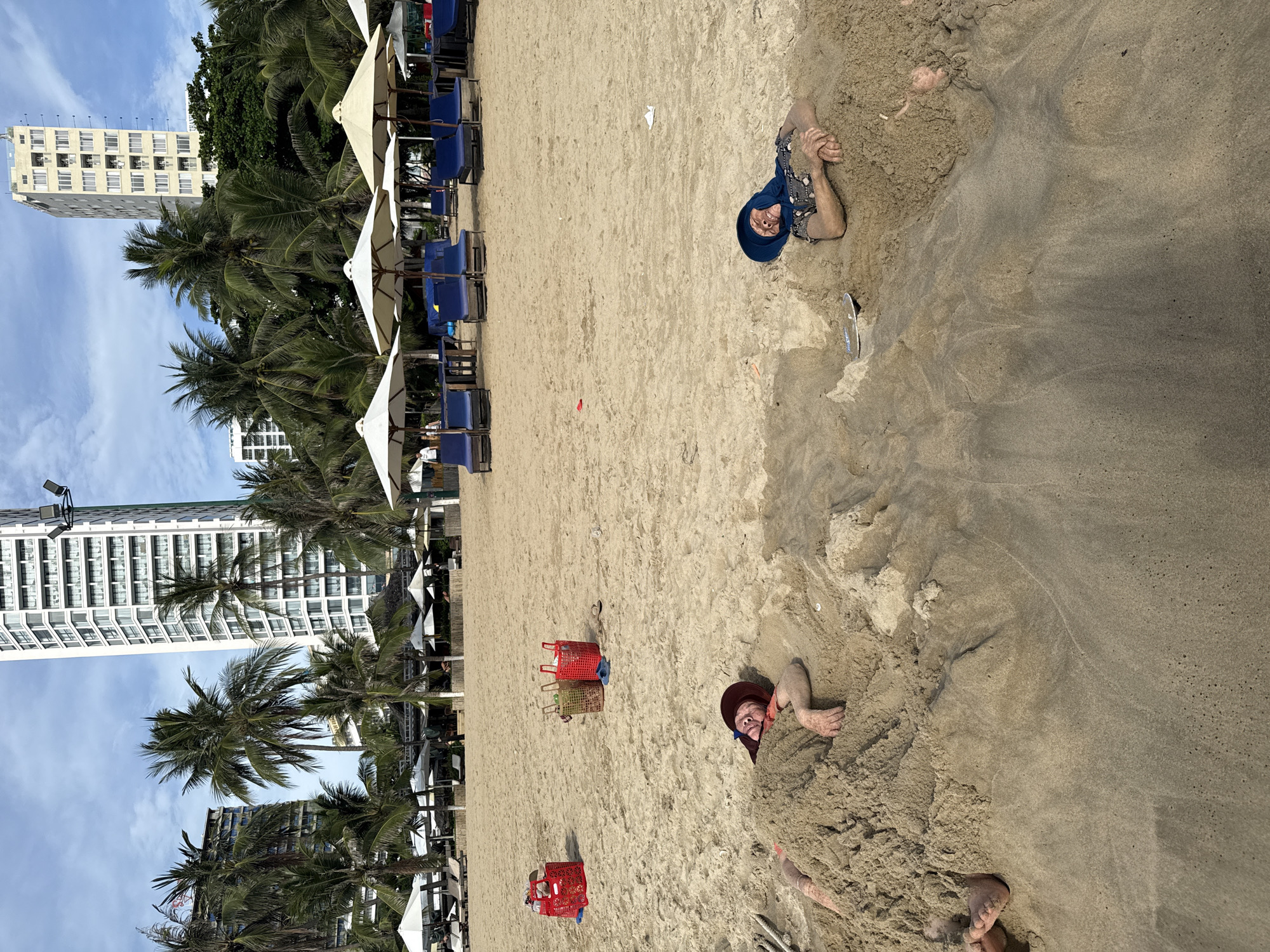 Buried up to their shoulders in the sand at Nha Trang beach.