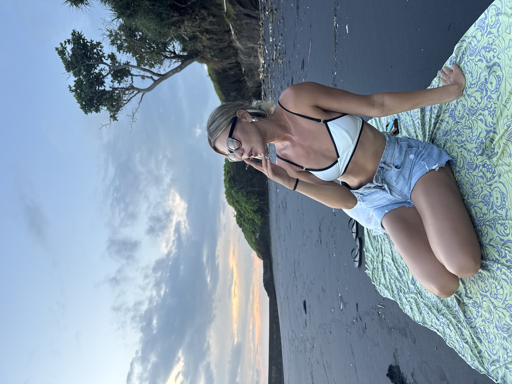 Woman smokes cigarette on black sand beach in Tabanan