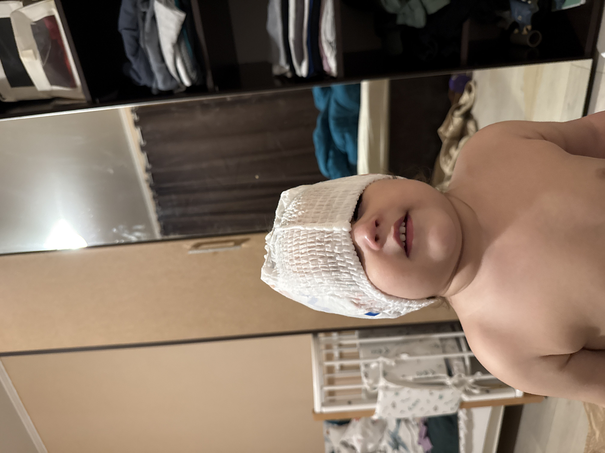 Child plays with diaper on head in Tobolsk bedroom