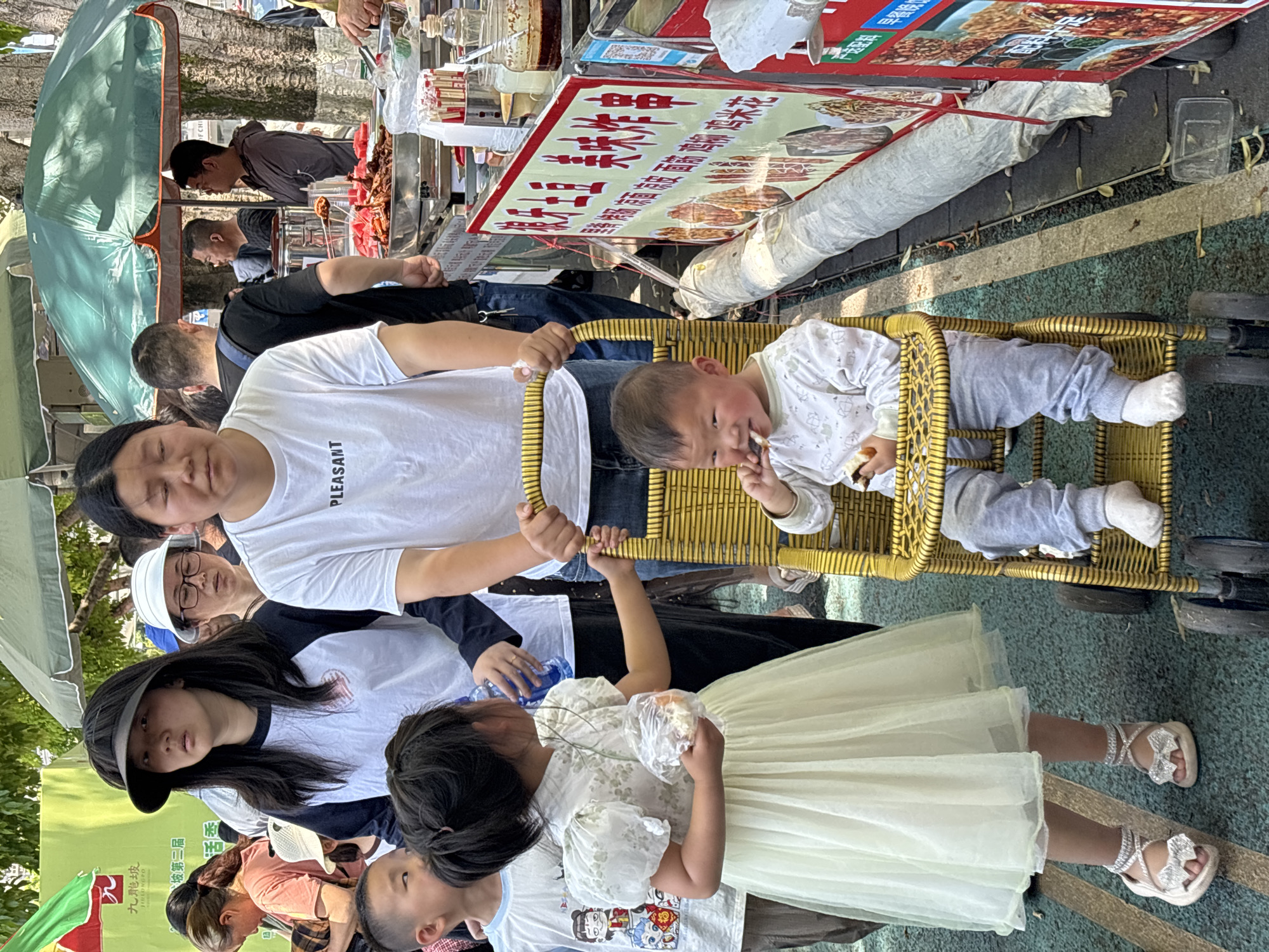 Family gathers outdoors in Jiulongpo District, baby feeds in chair