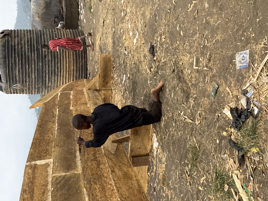 Young man kneels outdoors in Limbé III, Cameroon