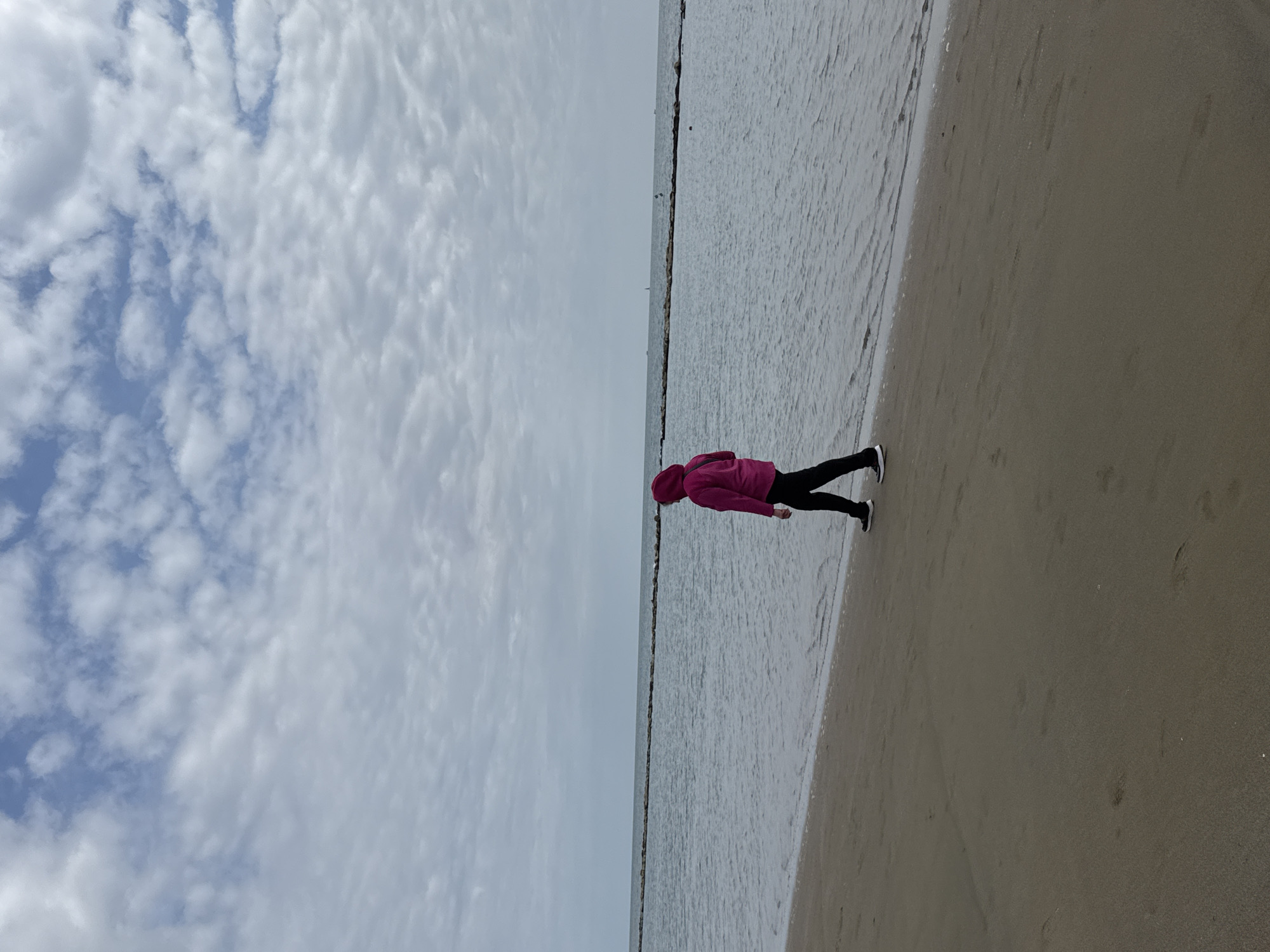 Beachgoers fish and stroll on overcast afternoon in Nettuno