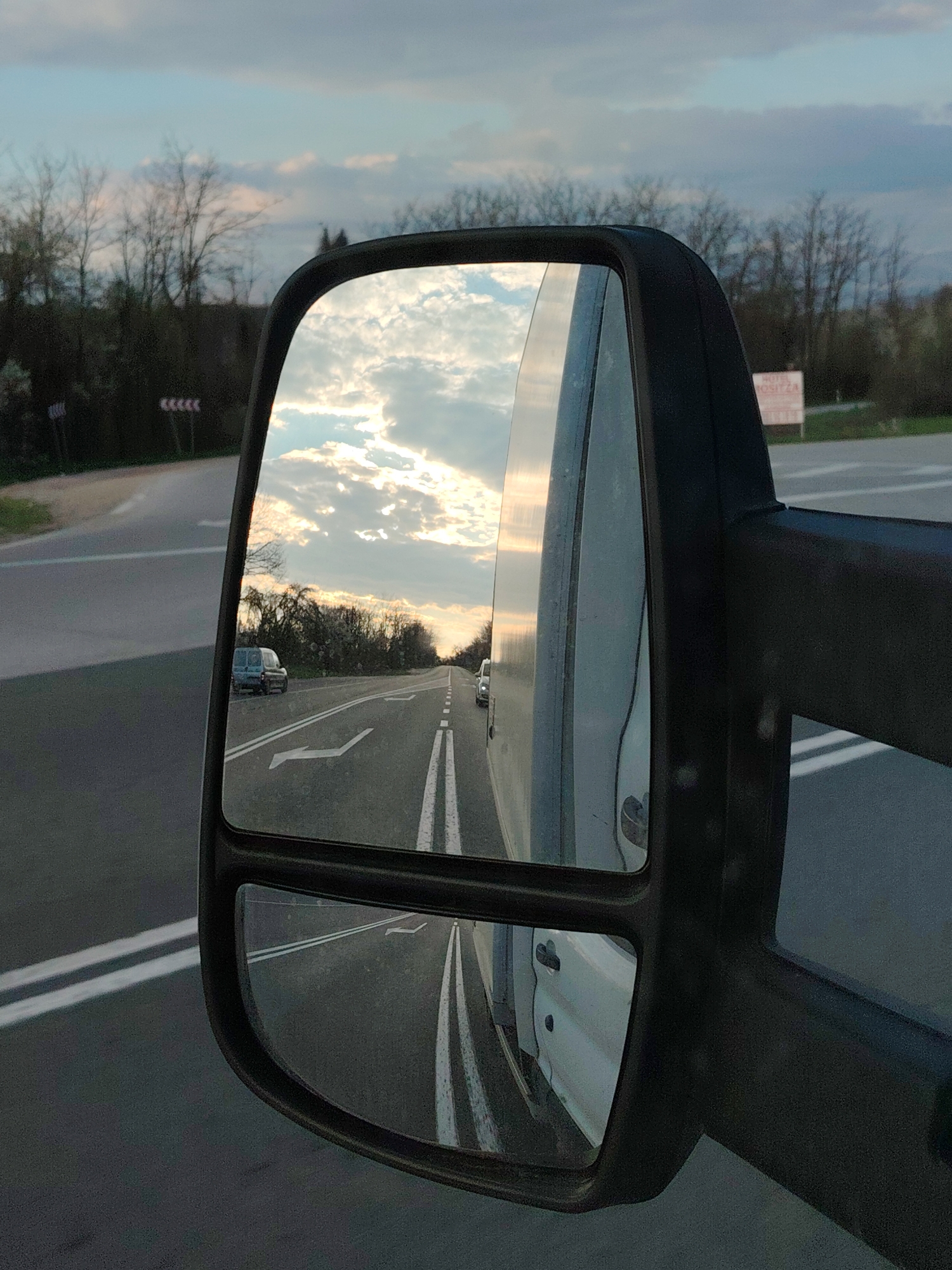 Van mirror reflects road scene at dusk in Bulgaria