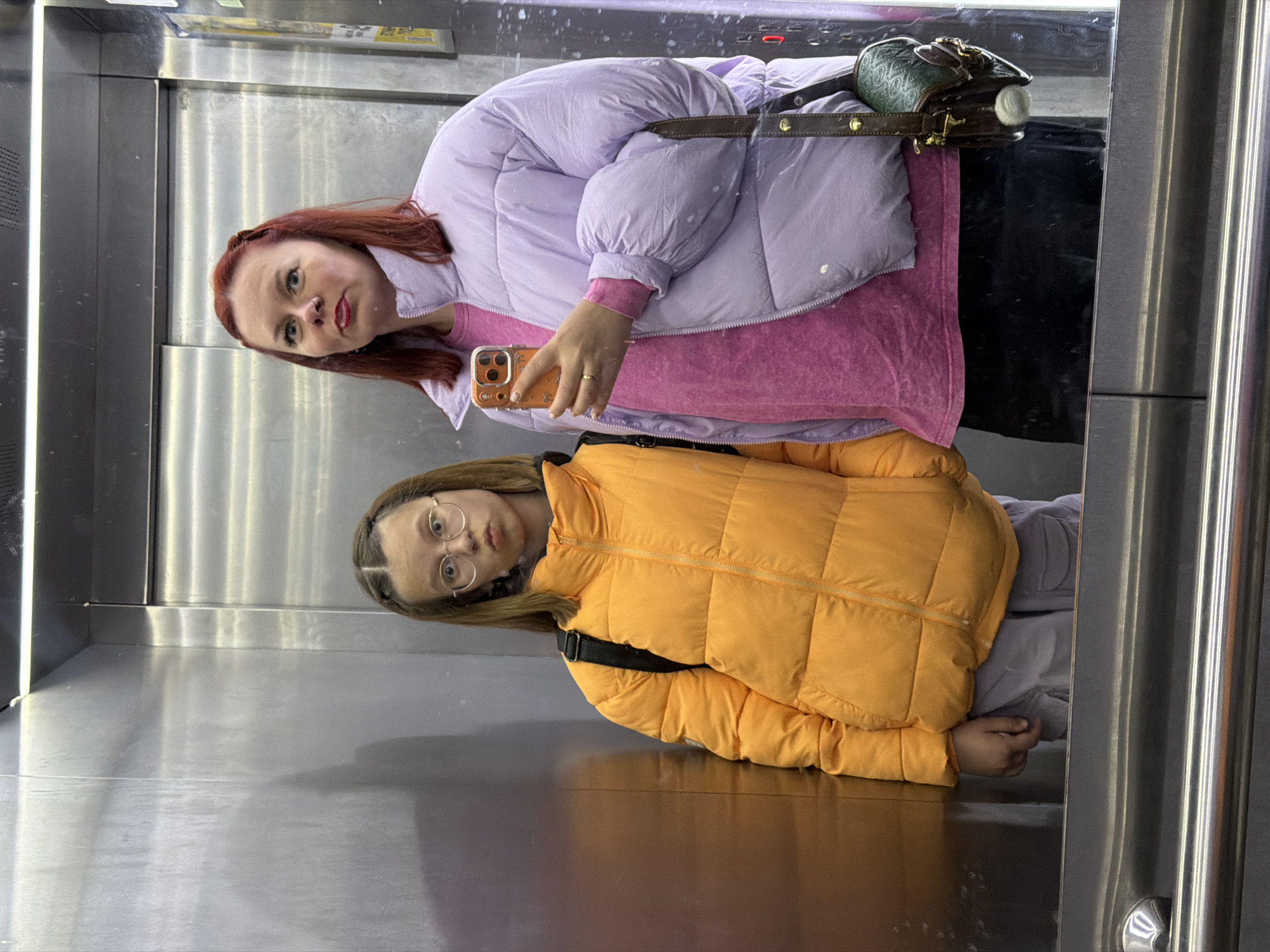 Two women spotted in mirrored elevator reflection