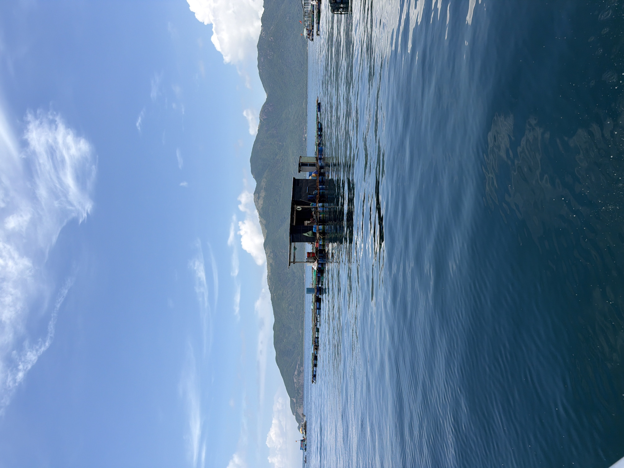 Boat approaches floating village near Vietnamese aquaculture farms