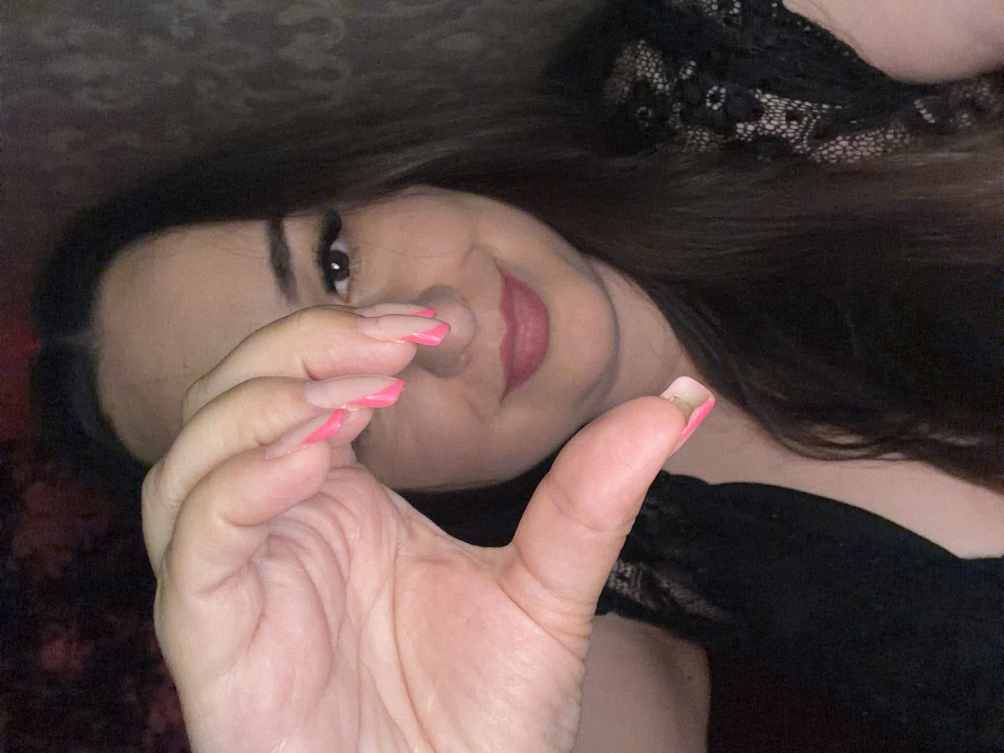 Close-up selfie session in a dimly lit room with red wallpaper.