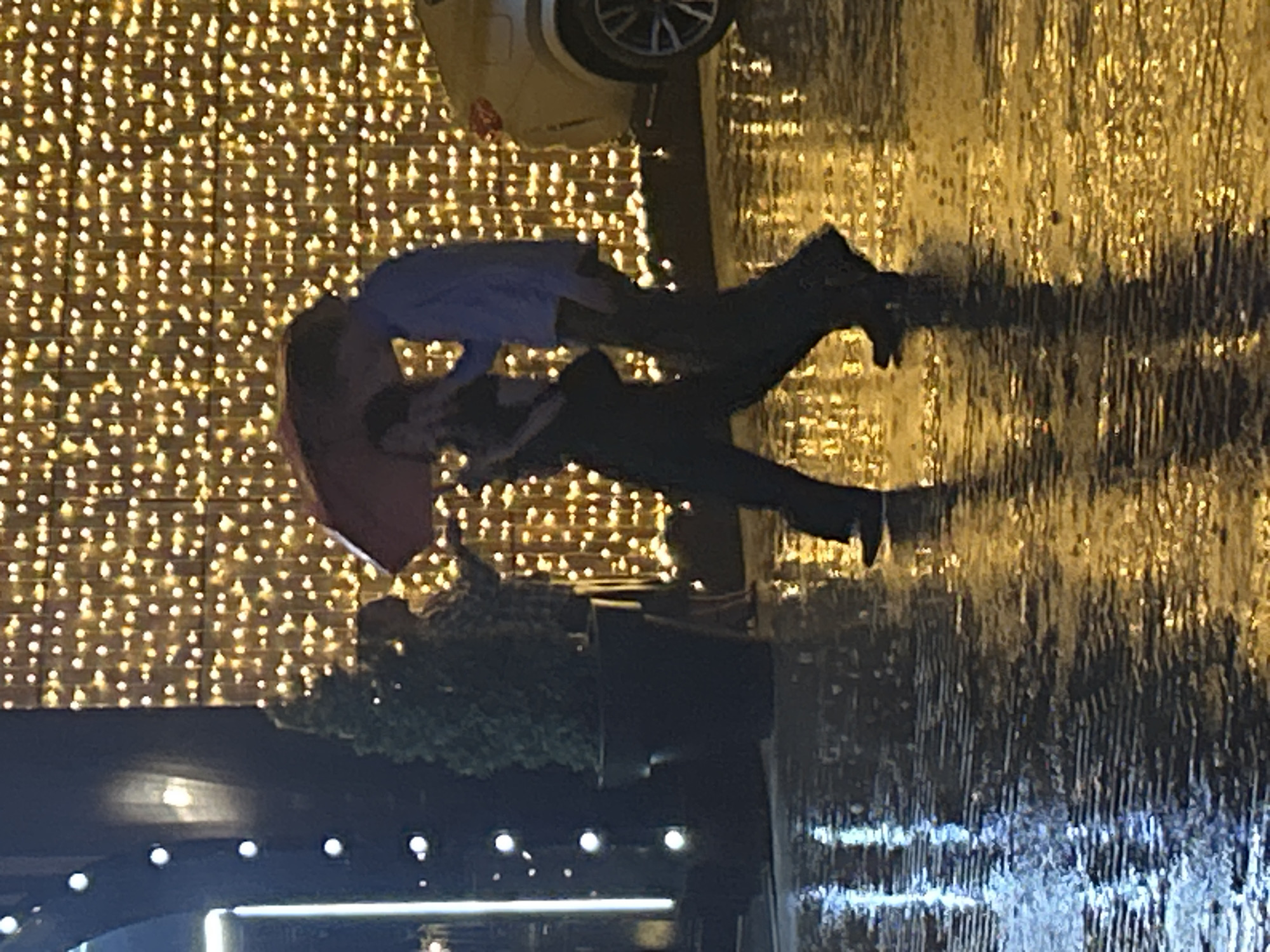 Nighttime rainstorm documented by witnesses sharing umbrellas, lightning